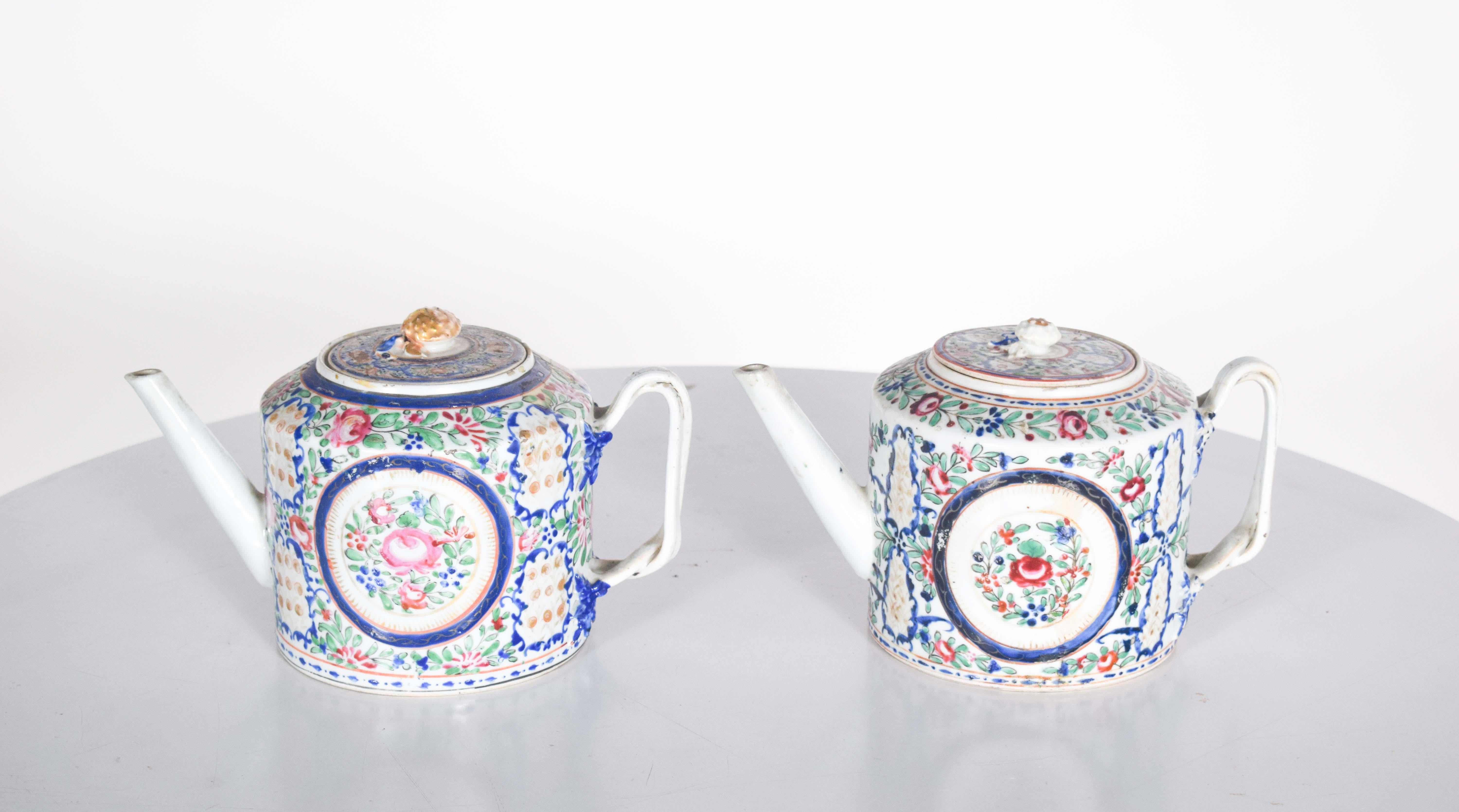 These two exquisite Chinese export porcelain teapots showcase intricate polychrome decorations featuring floral motifs in vibrant shades of blue, red, pink, green, and gold. The teapots have an elegant rectangular shape with slightly chamfered