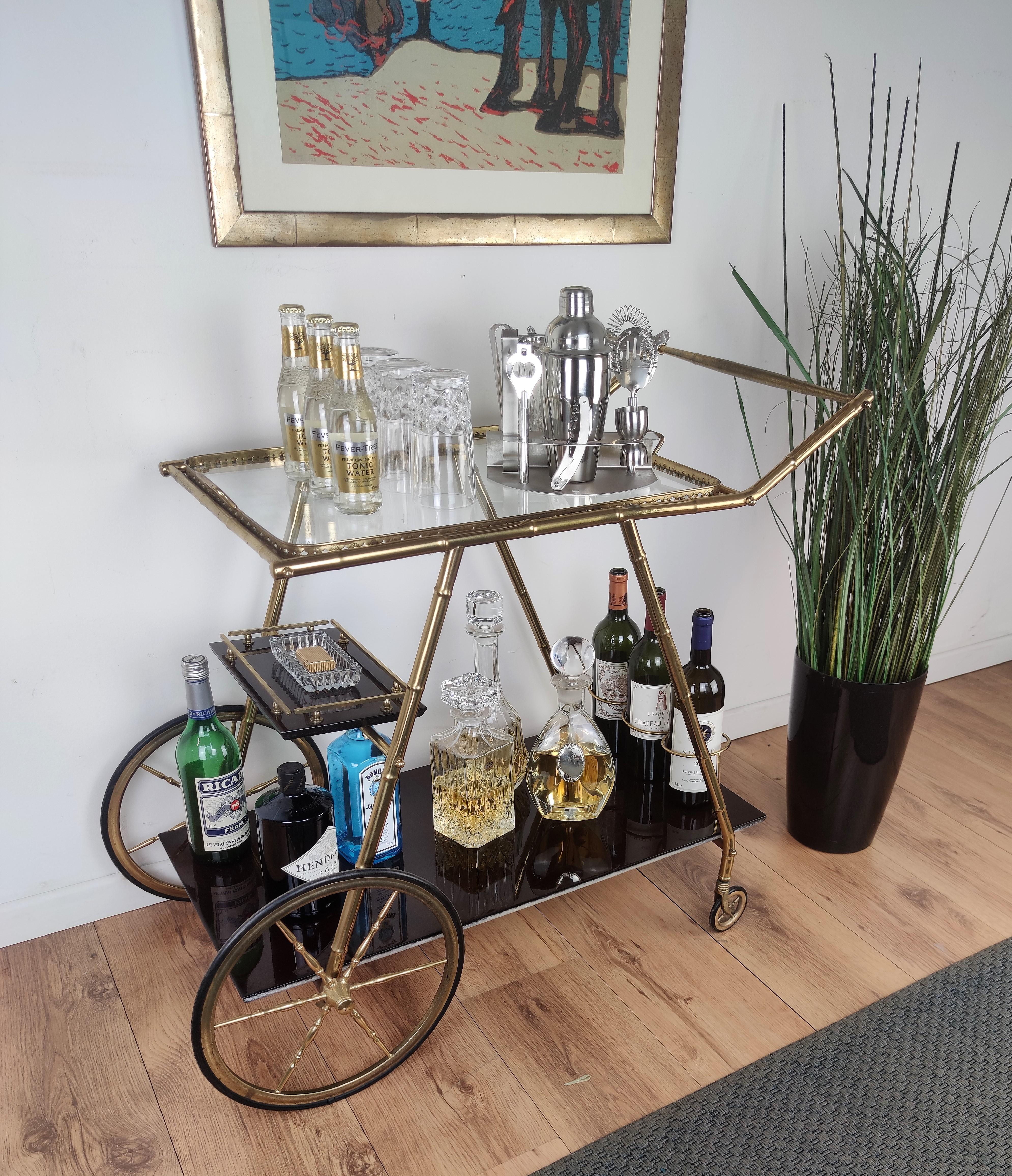 Beautiful and stylish vintage 1970s Italian two-tier brass and glass bar cart with removable top tray, great brass wheels and triple frame for bottle holder. Very good condition with minor wear on the cart and tray handles.

A great piece that