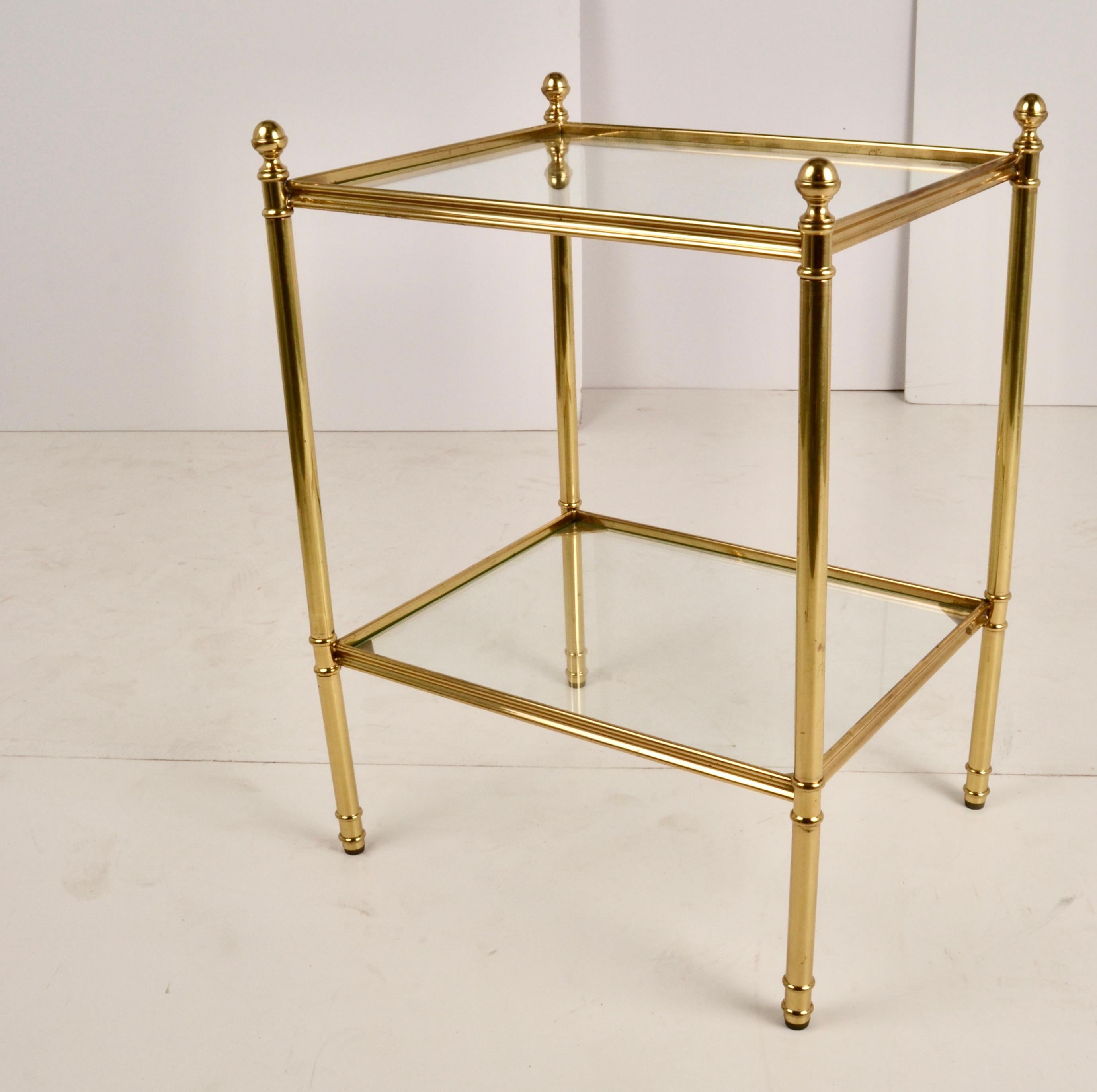 Classic two-tier brass side table with glass top and shelf. Turned round legs are topped with ball finials. Newly polished and lacquered.