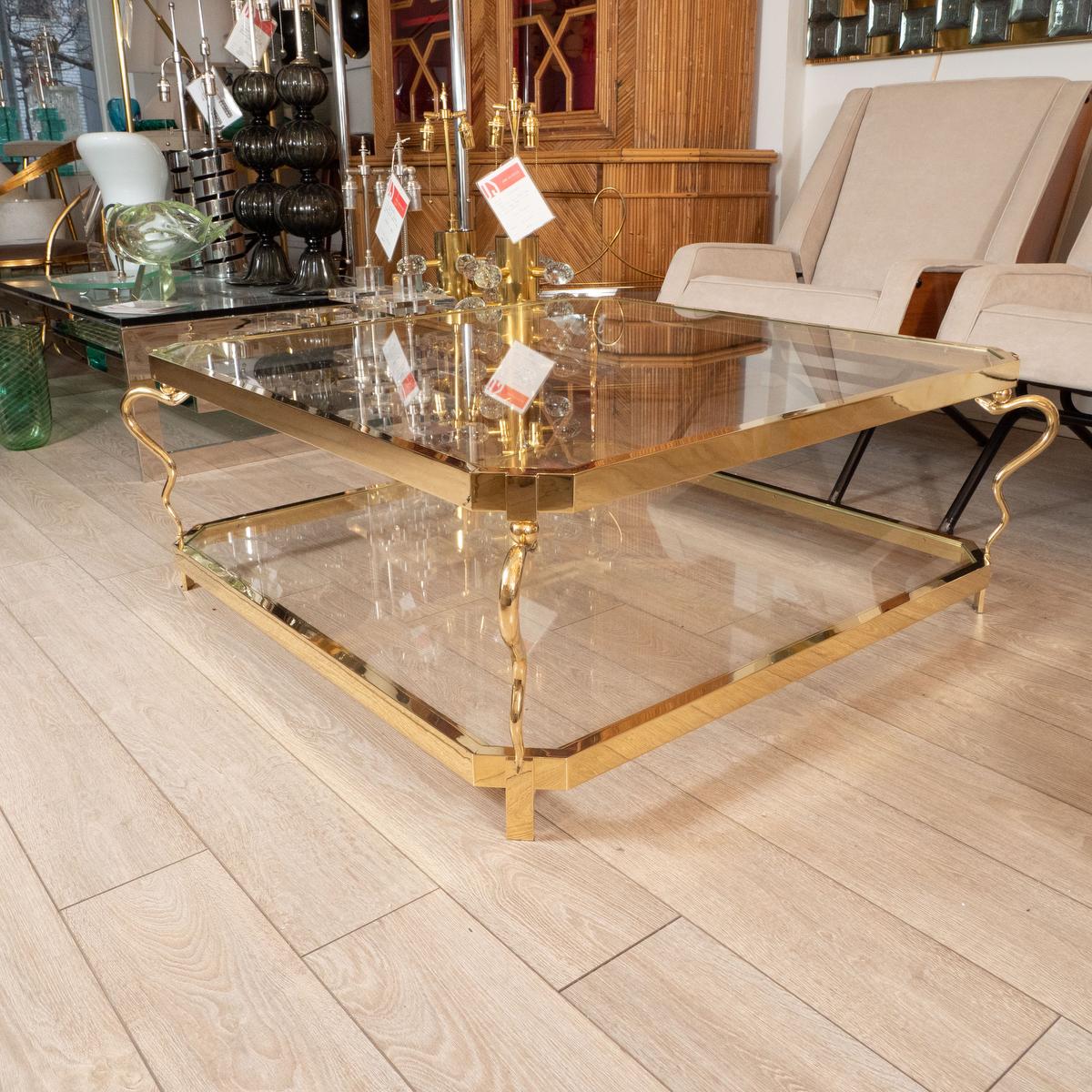 Two-tier brass coffee table with snake form supports at corners.

