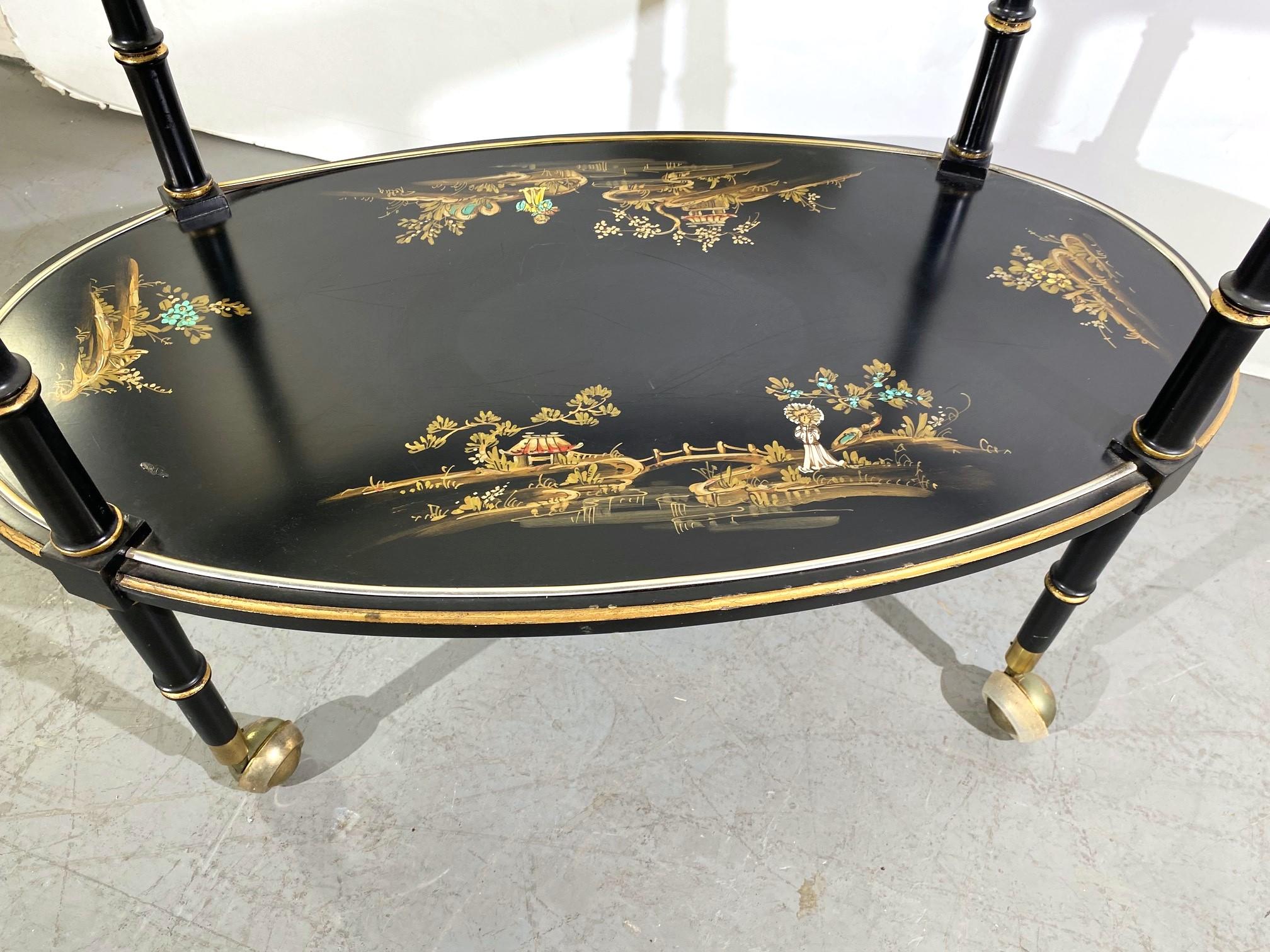 This is a two-tier Chinoiserie bar cart. The top tier has glass and brass railing, and the bottom tier is painted with the French motif.