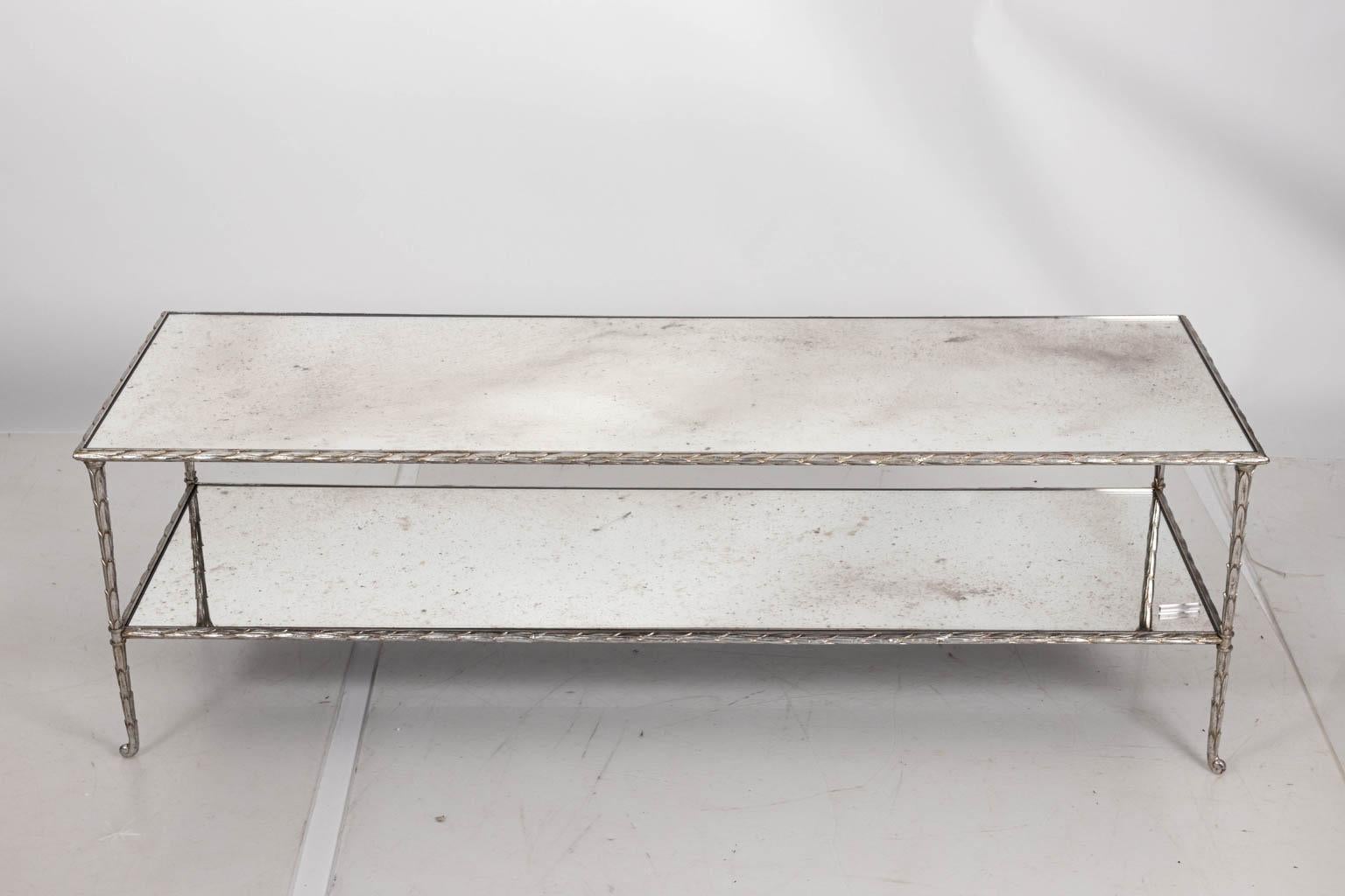 Two tier coffee table with silver leaf metal frame and mirrored glass top inserts. Please note of wear consistent with age including oxidation to the mirror plates and a distressed finish to the silver gilt.