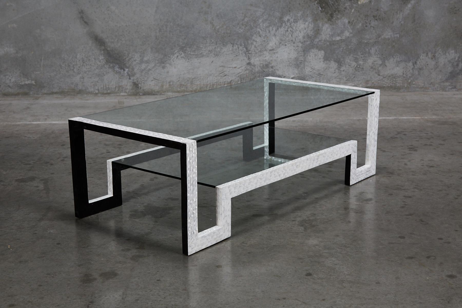 Two-tiered cocktail or coffee table. Thin, rectilinear frame hand-inlaid with iridescent white trocca seashell. Black tessellated stone detailing to inner edges. Two glass inserts form the tabletops. Very open and airy form, playing on the Classical