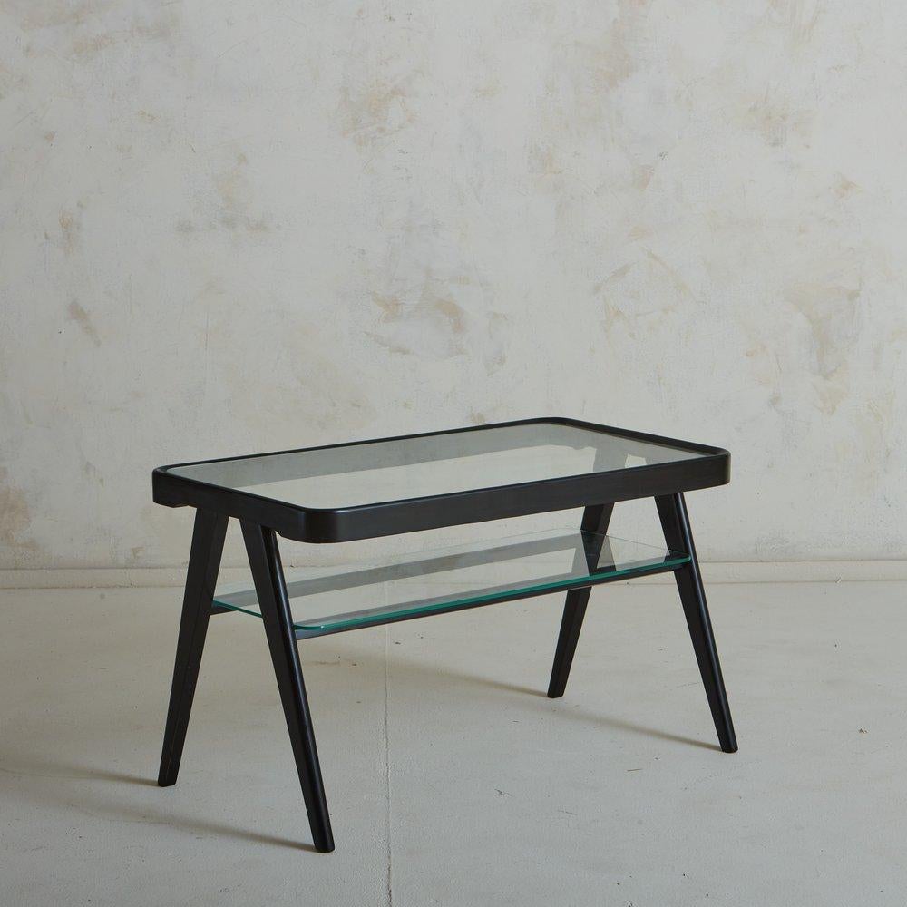 Ein italienischer Beistelltisch aus den 1960er Jahren mit einem Rahmen aus ebonisiertem Holz und dramatisch abgewinkelten, konischen Holzbeinen. Dieses Stück hat eine eingesetzte rechteckige Glastischplatte mit abgerundeten Kanten und eine