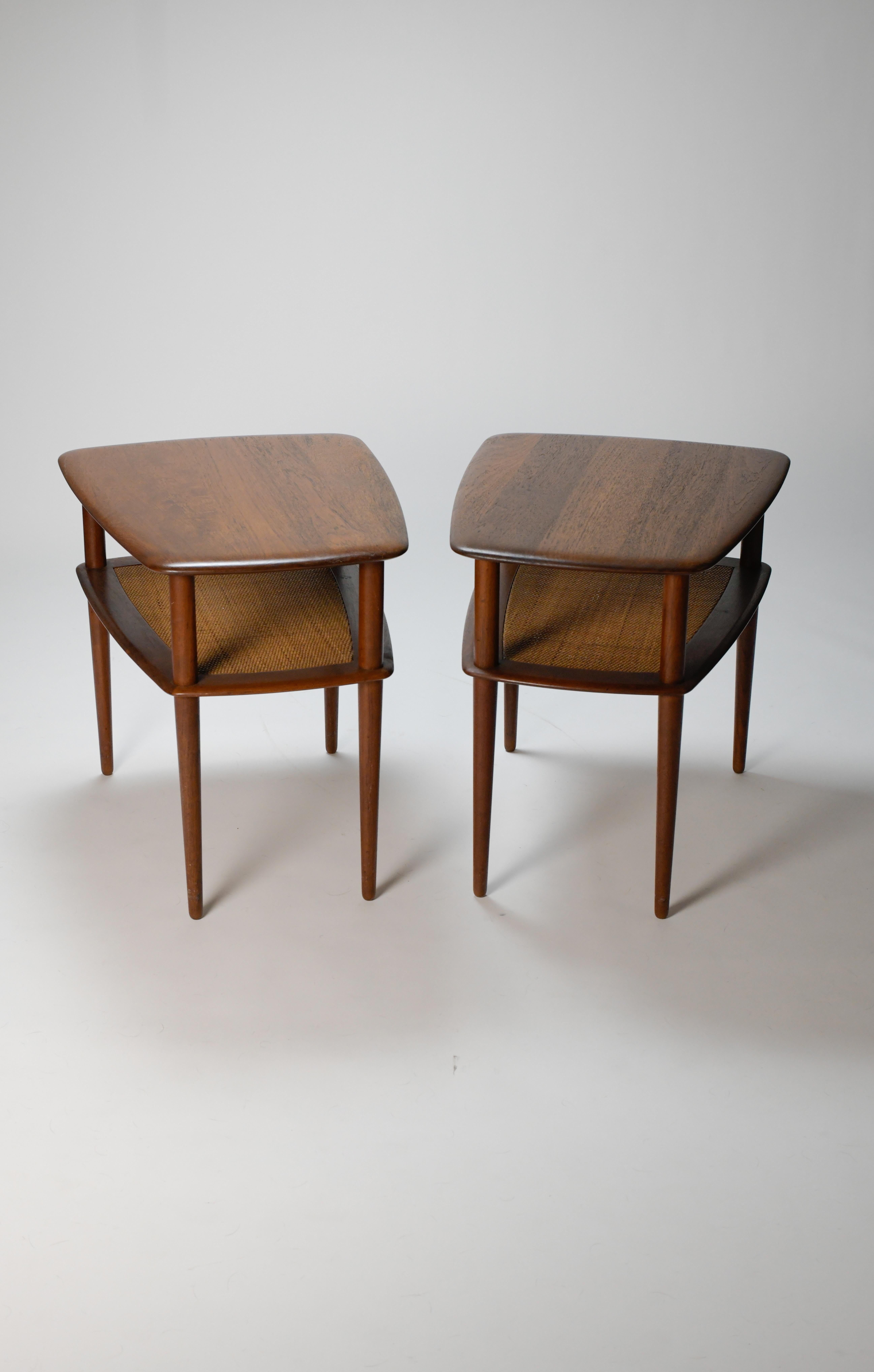 Really nice pair of the classic two tier side table designed by Peter Hvidt and Oral Molgaard Nielsen for France & Son. This asymmetrical table has an upper surface in teak with a lower shelf in cane. Both shelves on both tables are sturdy and have