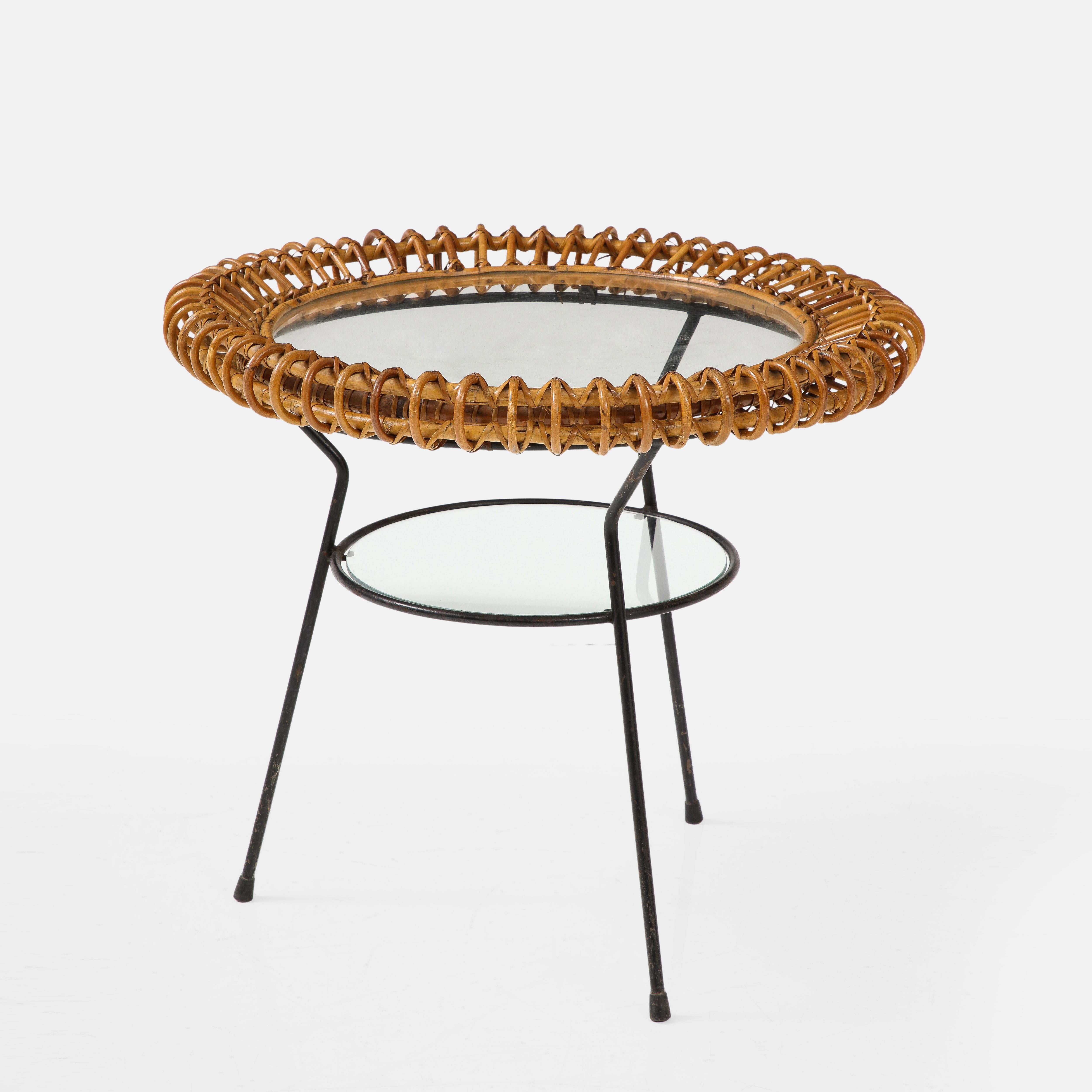 Bonacina round two-tier glass side table with woven bamboo and rattan surrounding a glass top on first tier, and round glass top on second tier all framed in black enameled metal frame. This chic Mid-Century Modern table has a beautifully woven and
