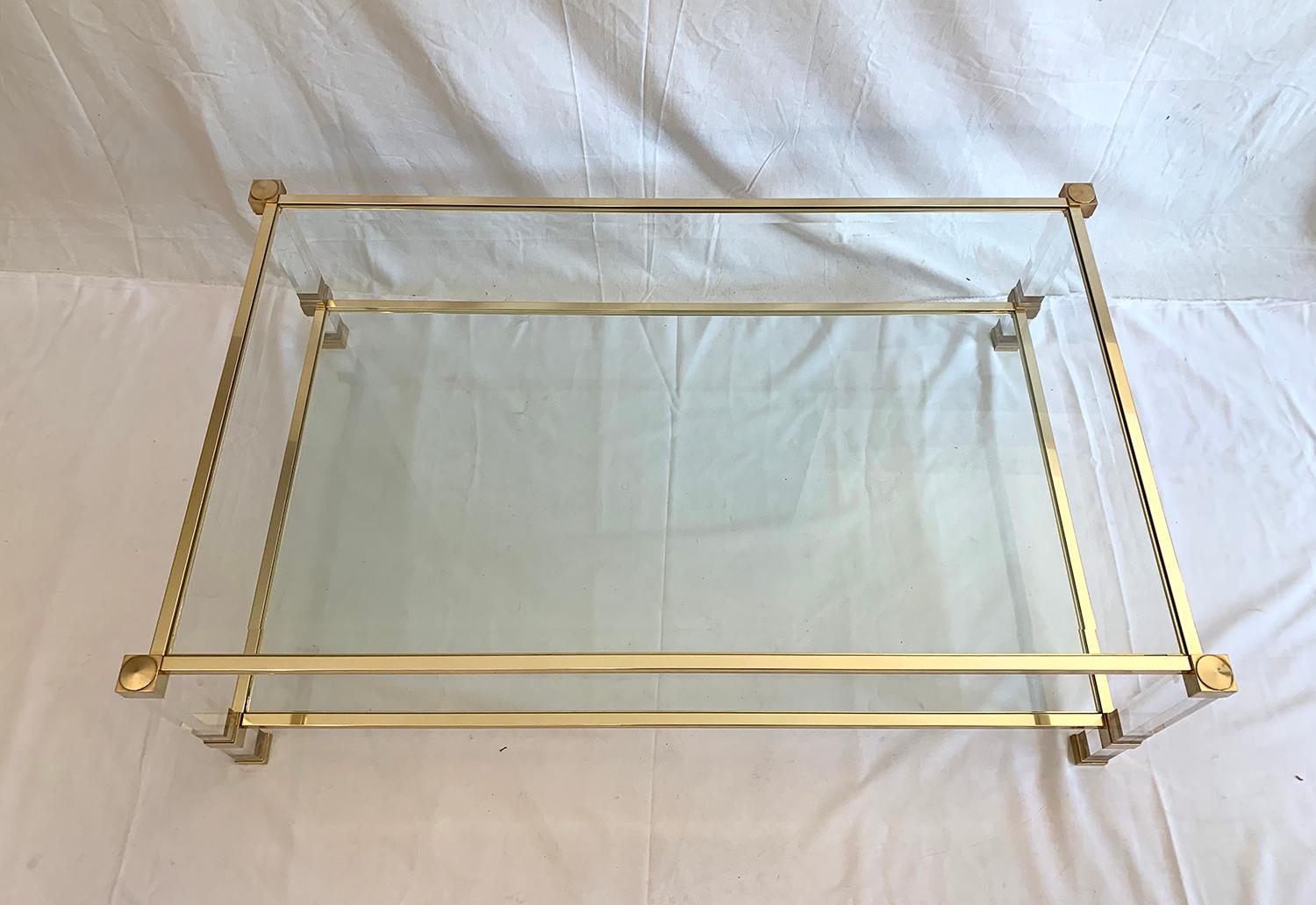 Superb coffee table with two levels designed by Pierre Vandel, 1970s. The brass and plexiglass plated metal structure displays two transparent glass trays, one of which is beveled. The table is in very good condition.

Superbe table basse à deux