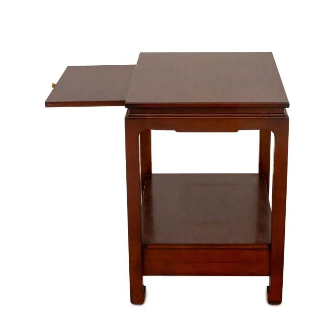 Dieser elegante und vielseitige zweistöckige Tisch ist aus edlem Mahagoniholz gefertigt und zeichnet sich durch ein elegantes Design mit asiatischen Einflüssen an Schürze und Beinen aus. Auf der oberen Ebene befindet sich eine diskrete, ausziehbare