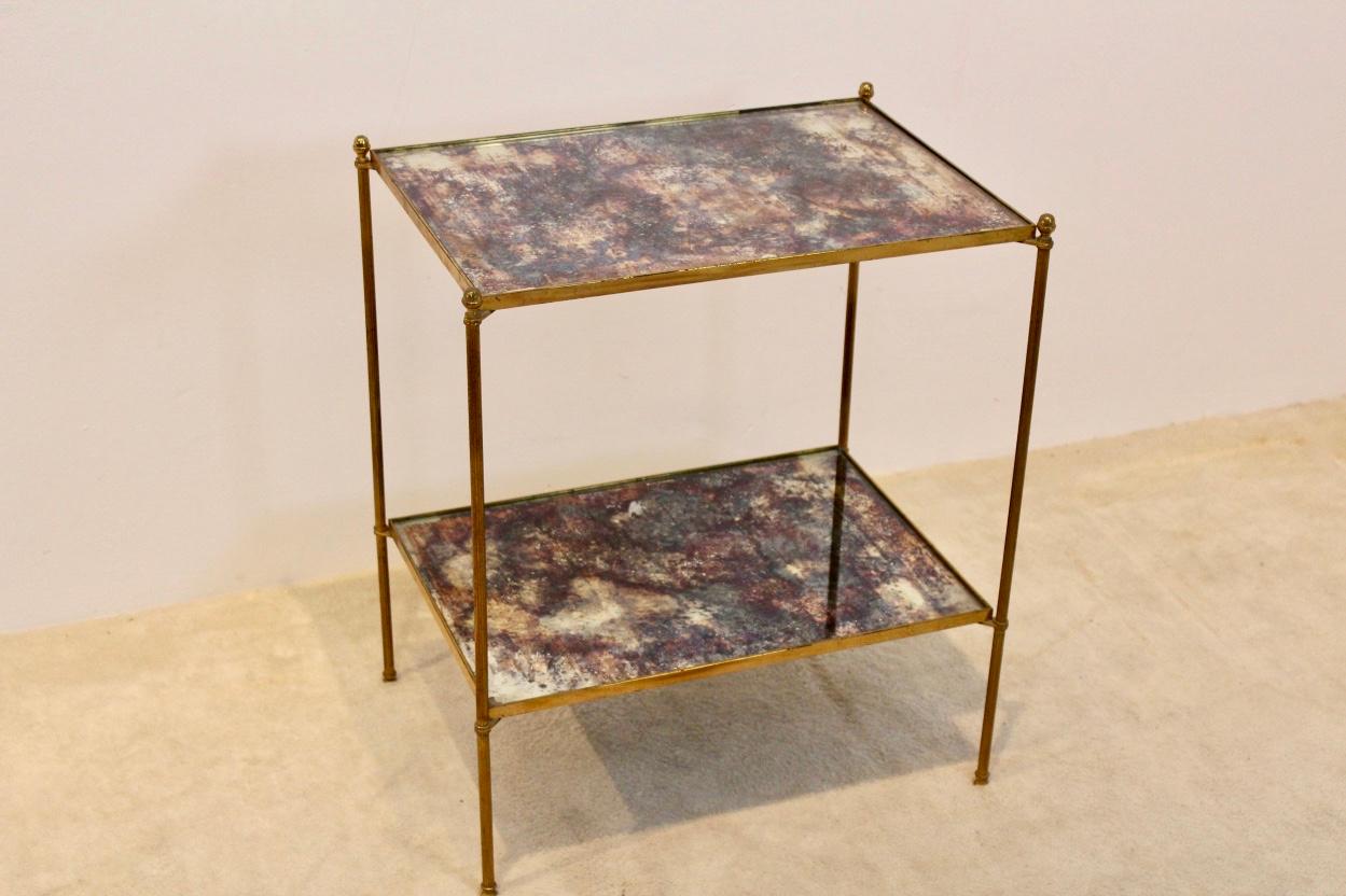 This gorgeous and elegant side table originates from France and was manufactured in the 1970s by Maison Charles. It features a brass frame with two tiers of glass in original bronze colored oxided olded mirror. A beautiful table of this famous