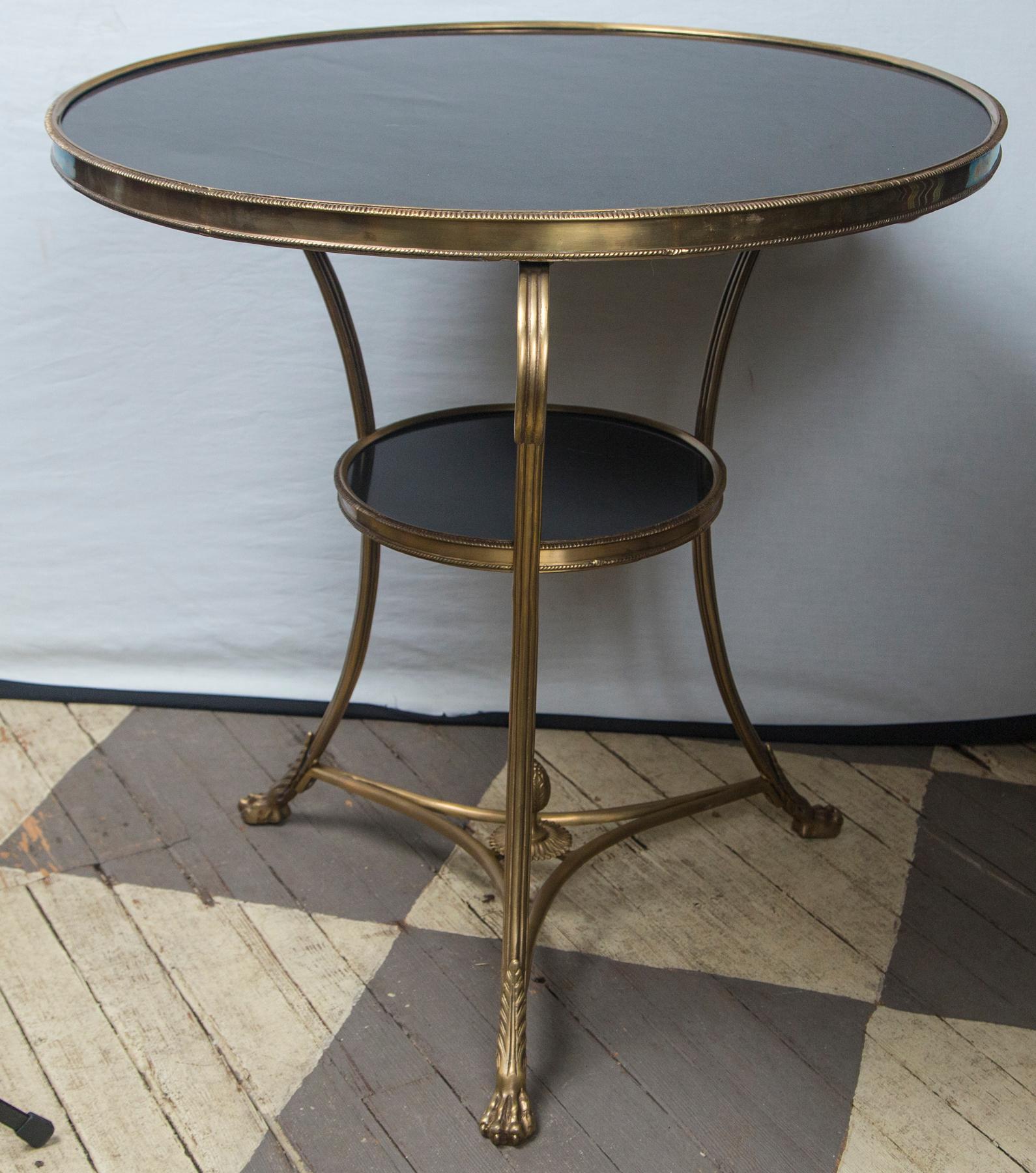 Made of solid brass with a black marble top and lower marble round, this table is in the Directoire style.
Gadrooned edge, dramatic scrolling legs, tripartite stretcher topped by an acorn finial. Casters missing
Lower shelf has a 12 inch diameter.