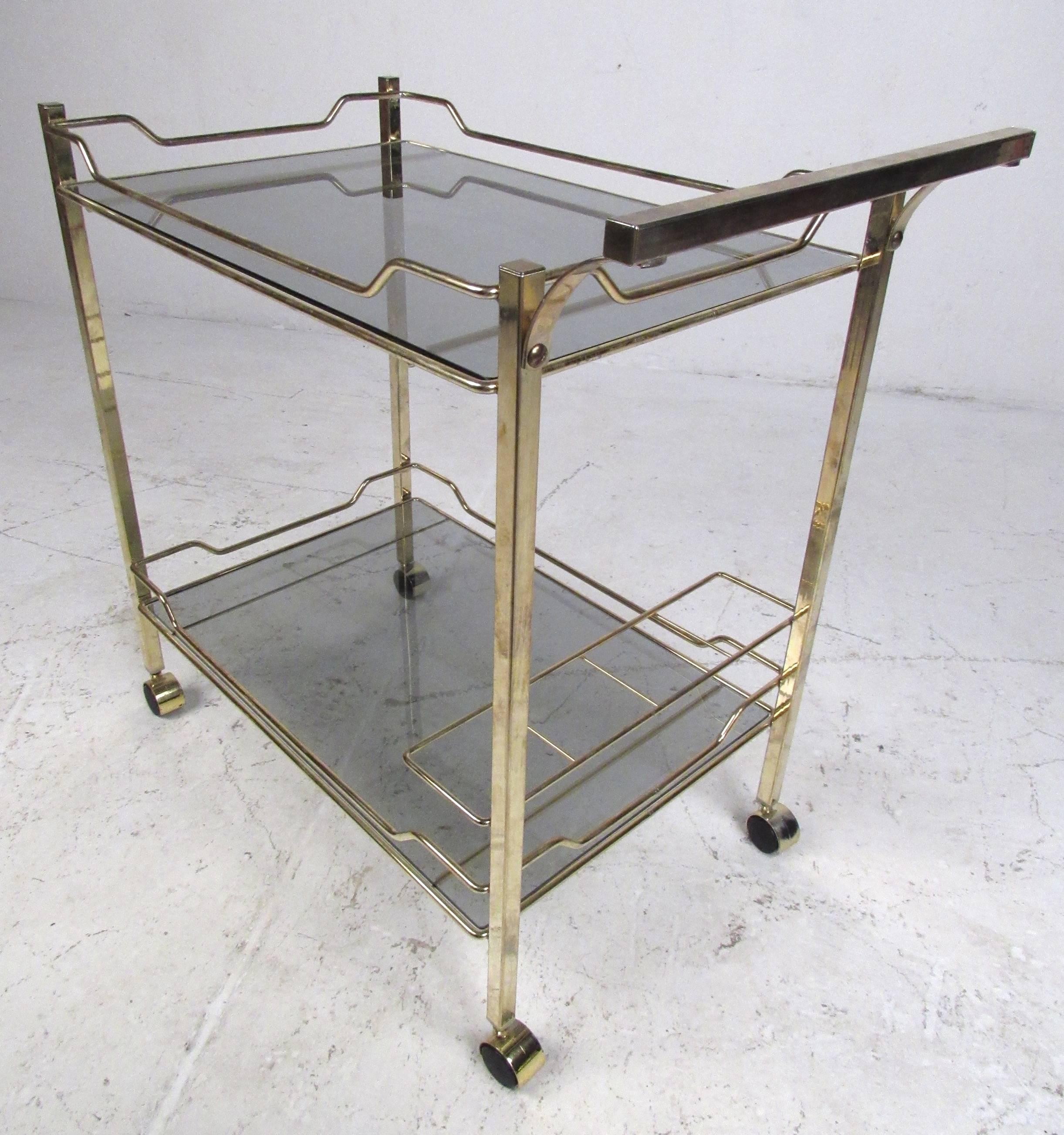 Brass finish serving cart with tinted glass shelves and lower tier bottle storage. Please confirm item location (NY or NJ) with dealer.
 