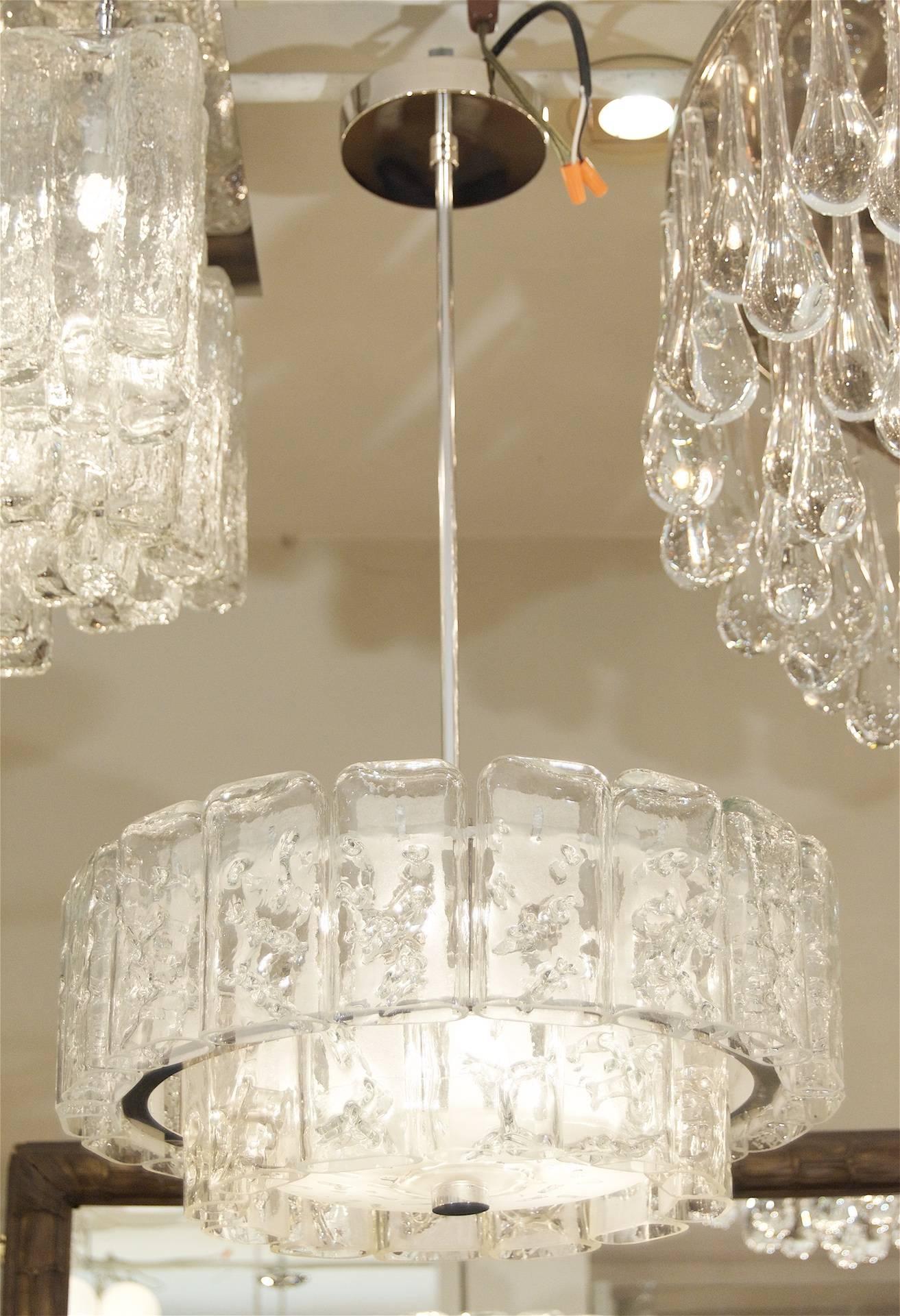 This fantastic and dramatic Doria chandelier is comprised of two tiers of individual glass pieces, with a central glass diffuser. The glass has the appearance of ice, each piece having internal random veining and a frosted reverse side. A thin