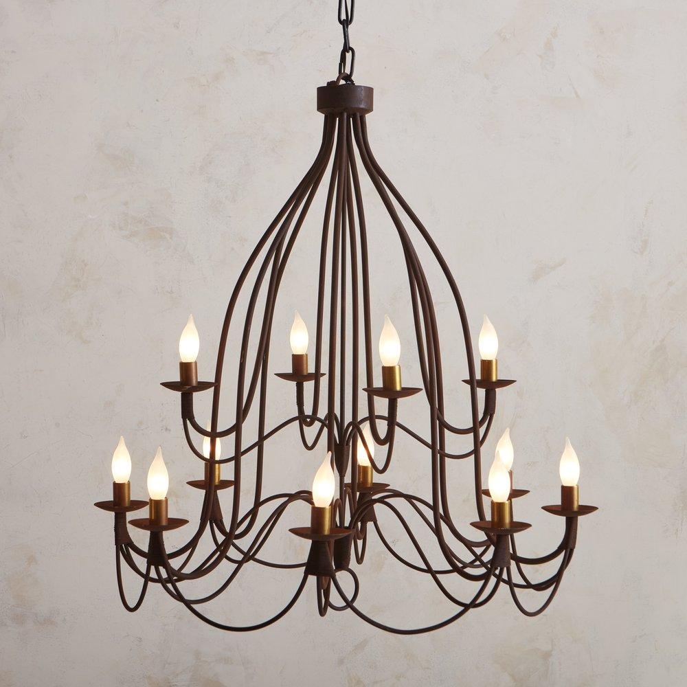 A large scale vintage Italian chandelier constructed with patinated iron. This piece features ten dramatically curved tubular arms, which branch outwards in two tiers. The arms intersect with a subtle wrapped wire detail and support 12 candelabra