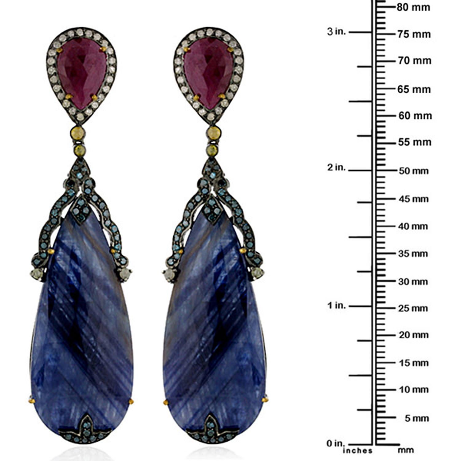 Impressive this Two-Tier Ruby and Sapphire Dangle Earring with Diamonds in 18k Gold and Silver can be worn from day to night.

Closure; Push Post

18KT Gold:2.22gms
Diamond:2.11cts
SiIver:12.35gms
Ruby:10cts
Blue Sapphire:66.7cts
