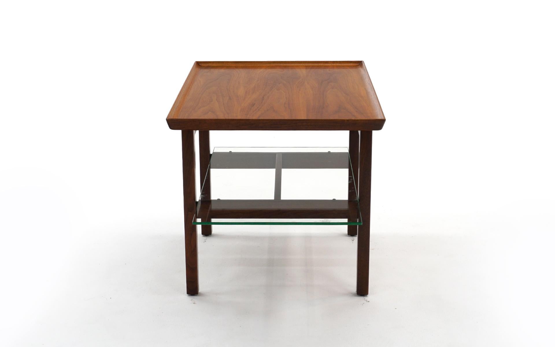 Cantilevered side / end table with lower glass shelf designed by Jens Risom. Beautiful Walnut construction with few examples of wear. The glass shelf has one tiny corner ship that is not apparent when on the table. Signed with the Risom Design label.