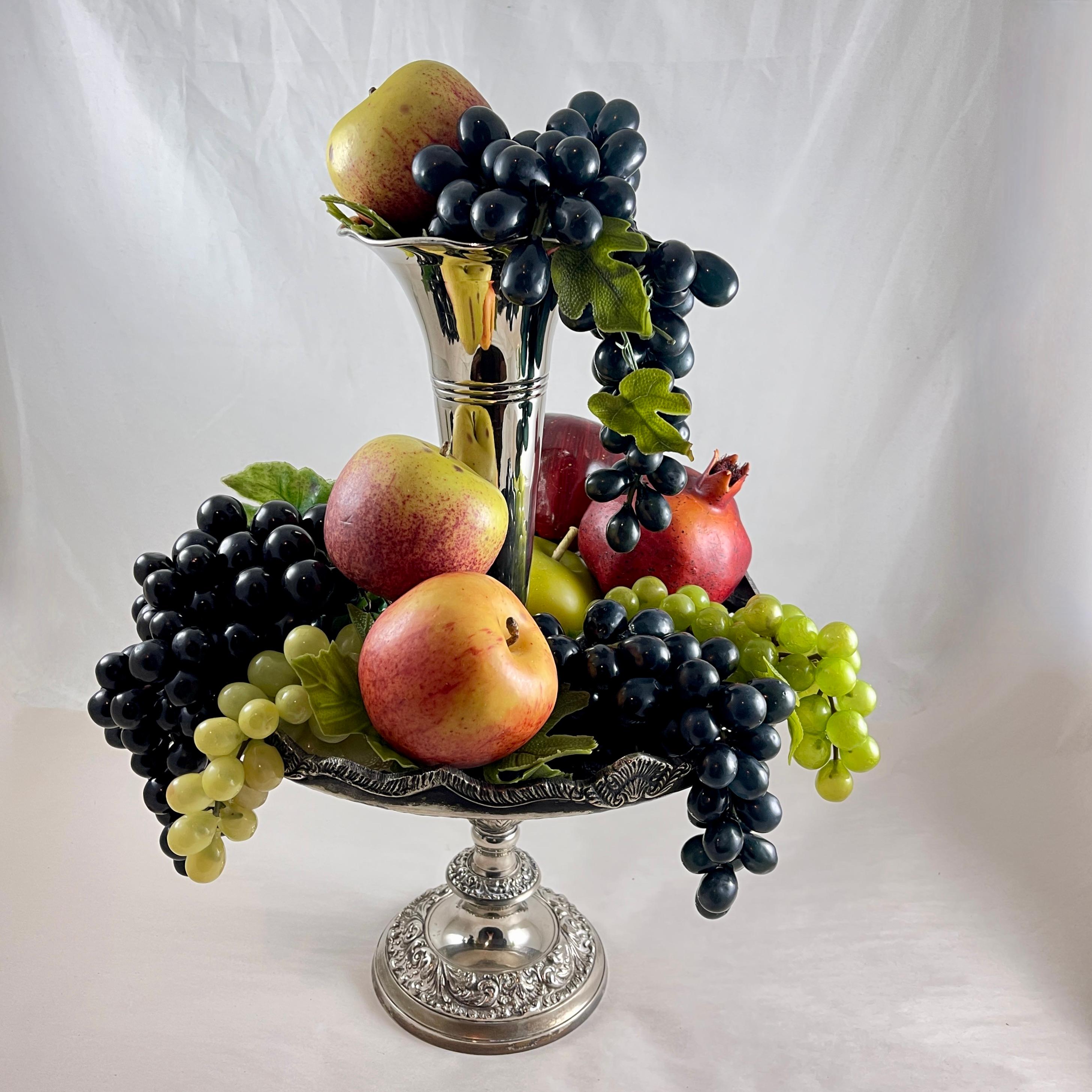 A silver plated two-tiered Epergne,  American, circa 1920-1930.

An Epergne is an ornamental centerpiece for a dining table or sideboard, typically used for holding fruit or flowers.

This Epergne is made of four separate pieces that fit together –
