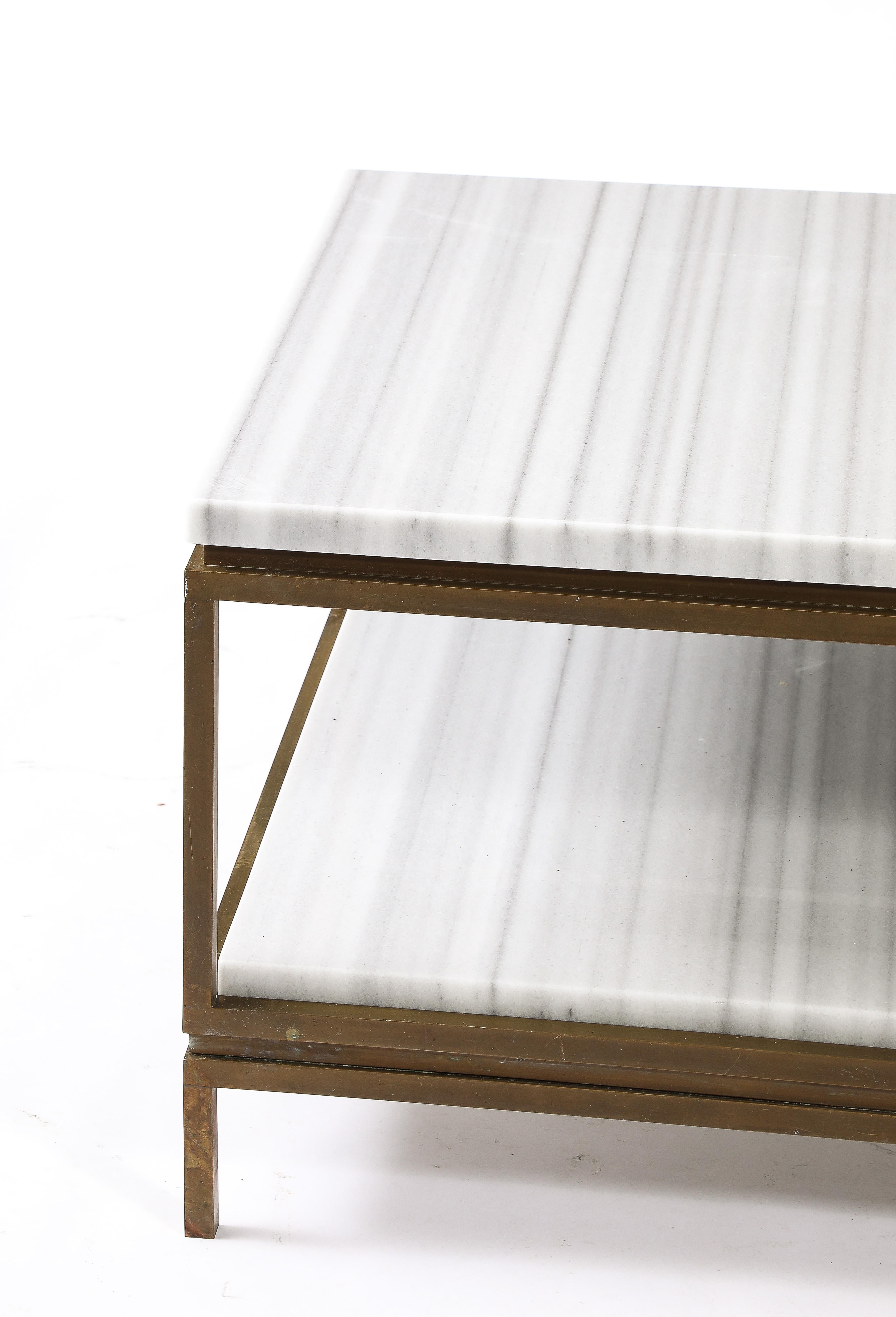 Elegante table basse avec niveau inférieur encastré et plateau surélevé, chaque niveau ayant un épais plateau de marbre rayé.
