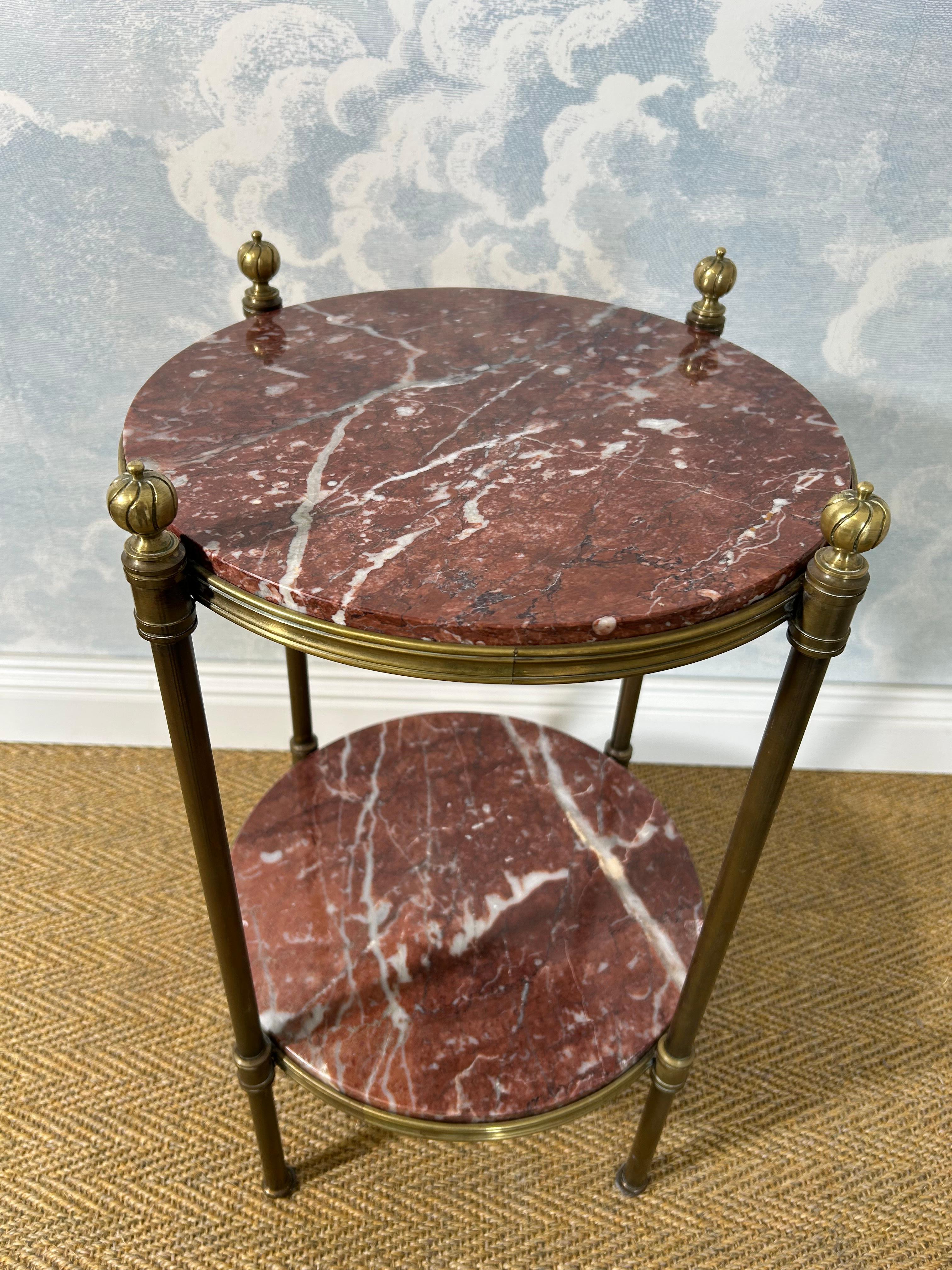 Les épis de faîtage en laiton nervuré et les plateaux en marbre confèrent à cette jolie petite table d'appoint un aspect plutôt sophistiqué.

Posés sur un cadre en laiton à quatre pieds, le plateau circulaire en marbre et l'étagère assortie sont en