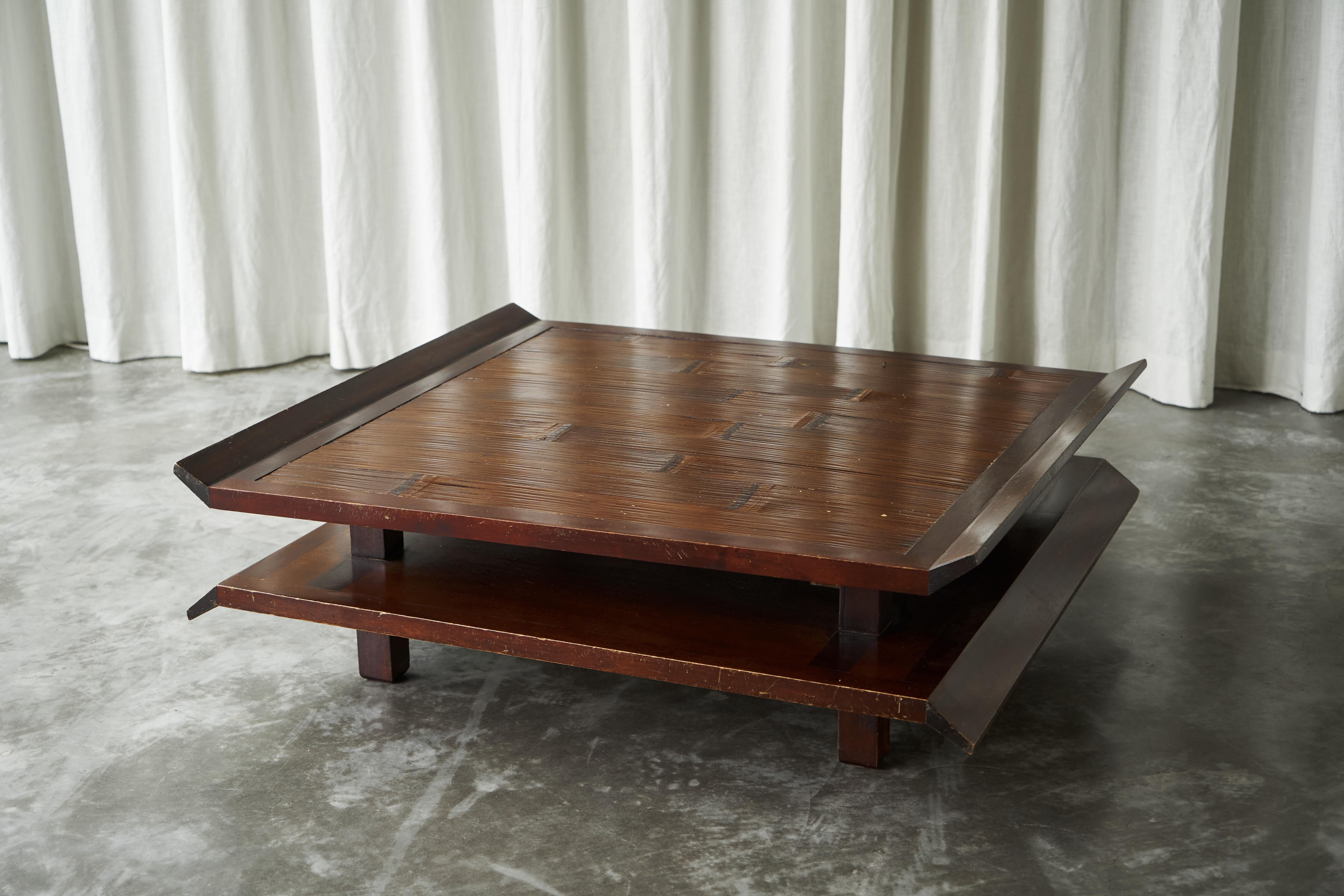 Zweistufiger japanischer Couchtisch im Pagodenstil aus Holz und Bambus, 1970er Jahre.

Es handelt sich um ein markantes Stück mit klaren architektonischen Qualitäten. Der Tisch hat eine quadratische Platte mit erhabenen Kanten, in die Bambus
