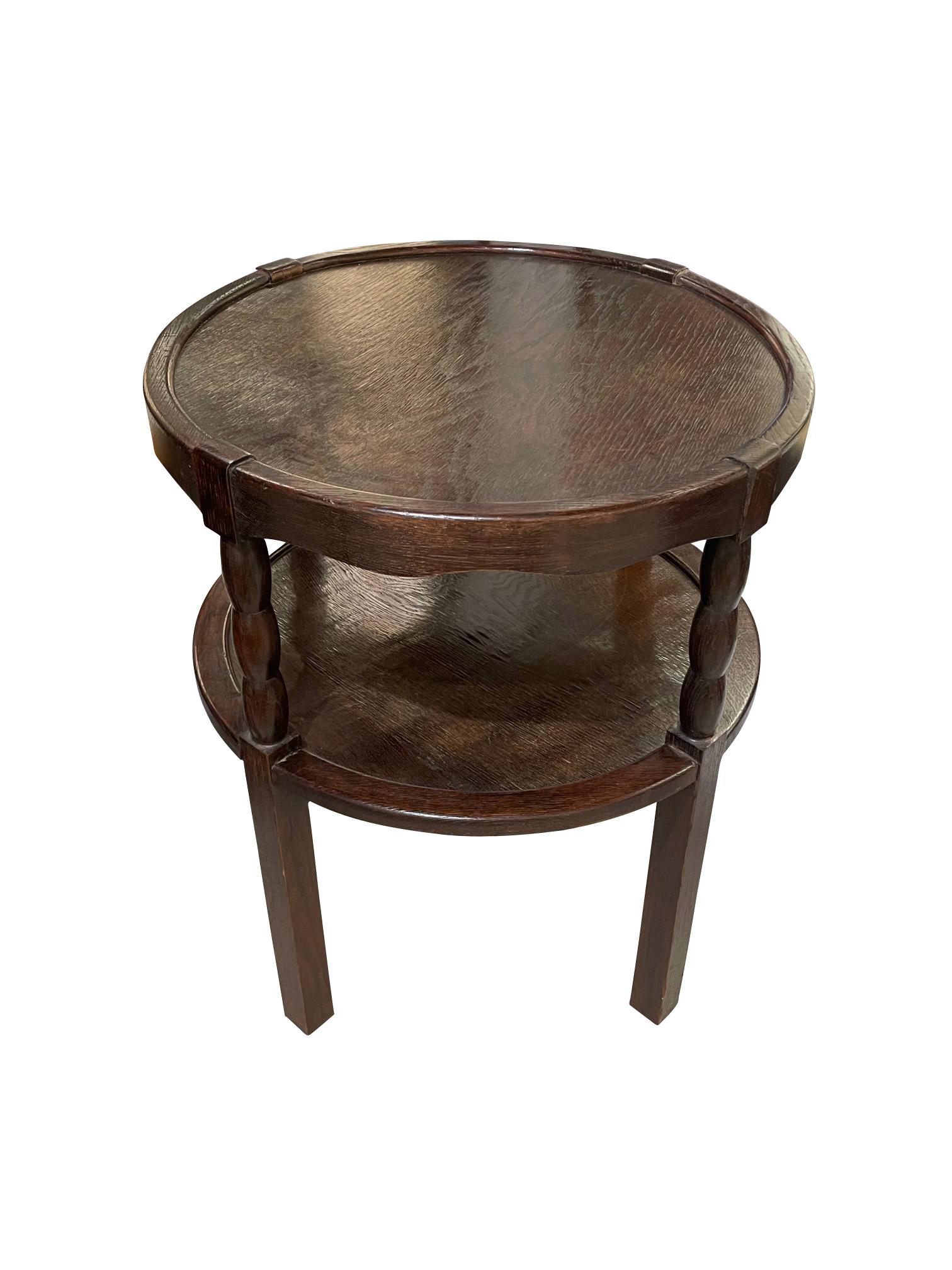 1930's French two tiered round side table.
Lip detail around both surfaces.
Spool design connecting two tiers with square leg bottom.
Polished oak wood.
Recently refurbished.