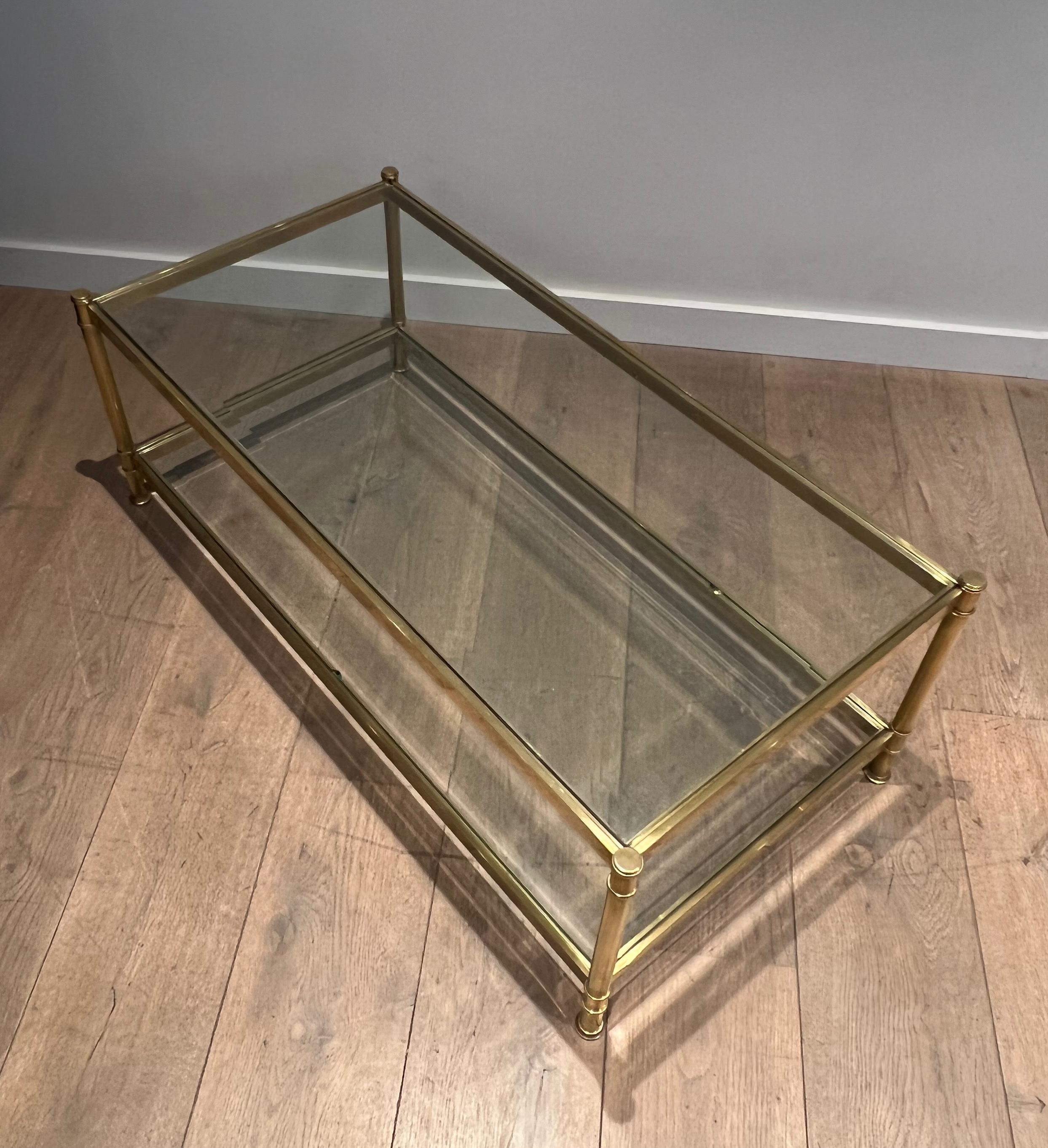 This very nice two tiers coffee table is made of brass with 2 clear glass shelves. The top glass shelf is beveled all around. This is a French work by Roche Bobois. Circa 1970