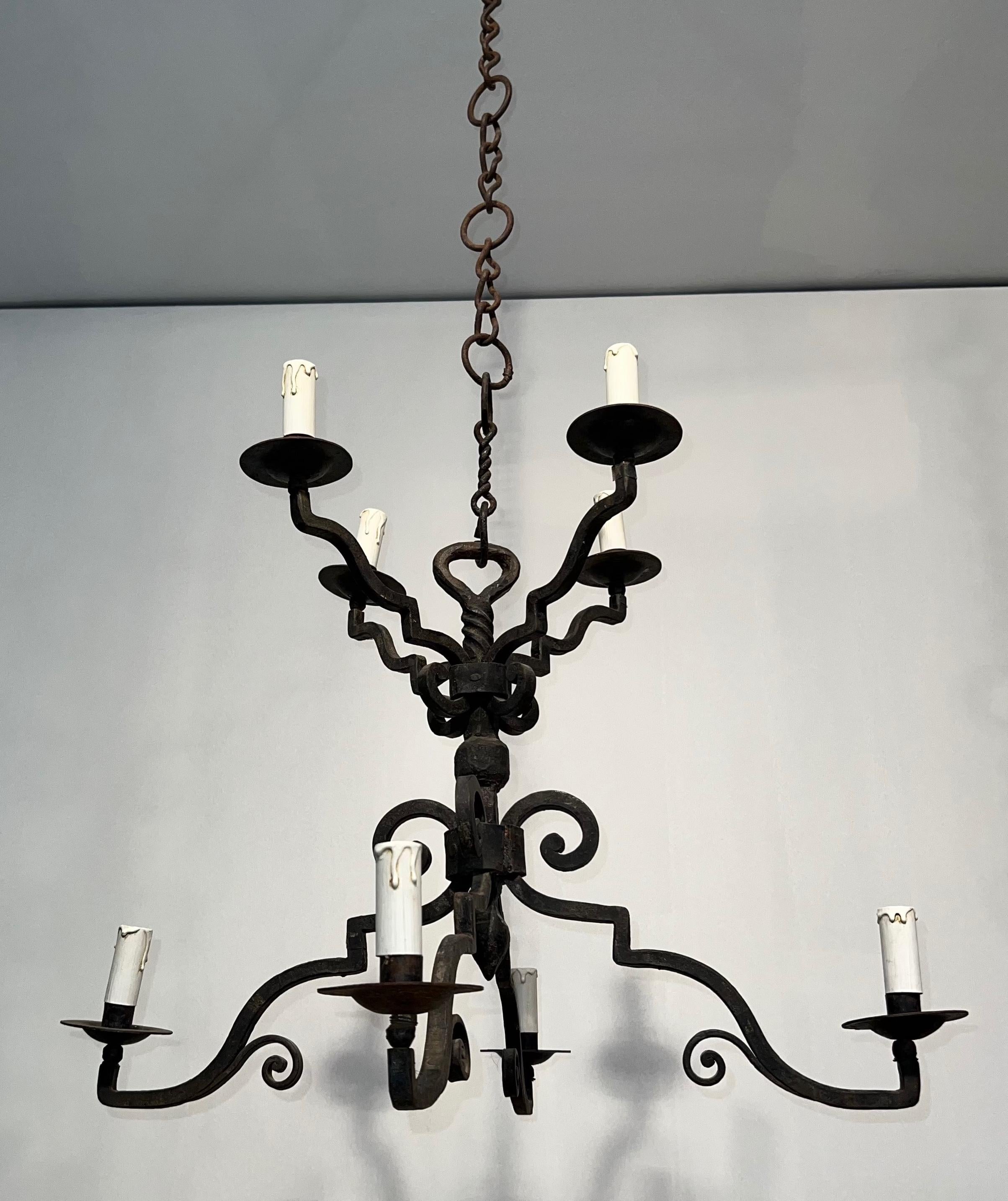 Questo simpatico e insolito lampadario a 8 bracci è realizzato in ferro battuto. Si tratta di un'opera francese in stile gotico. Circa 1920