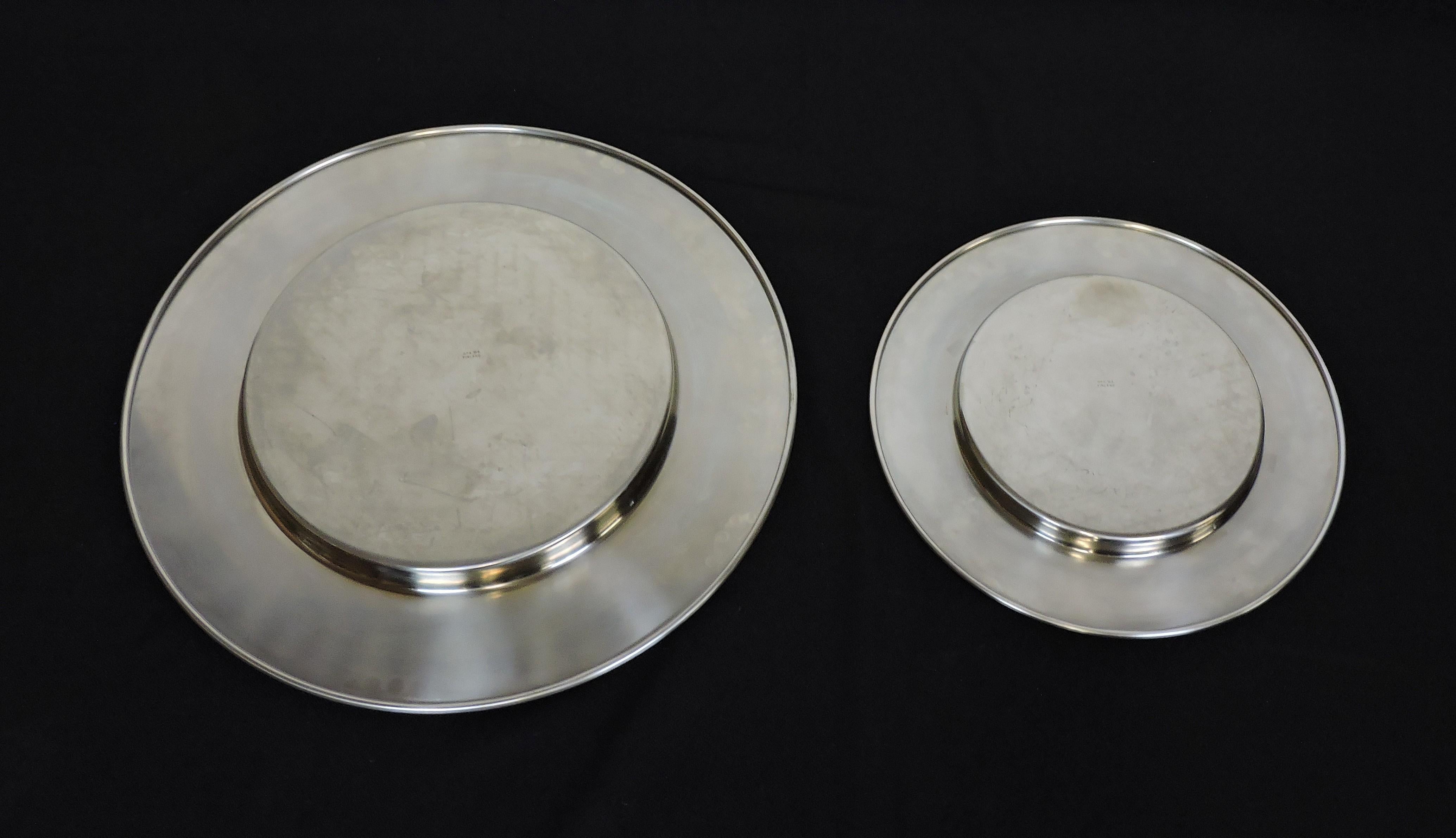Hard to find set of two stainless steel platters designed by Timo Sarpaneva and made in Finland by OPA Ltd. Designed in 1970, the large platter is model TS-300-62 (62 cm), and the smaller platter is TS-300-44 (44 cm). The larger platter is