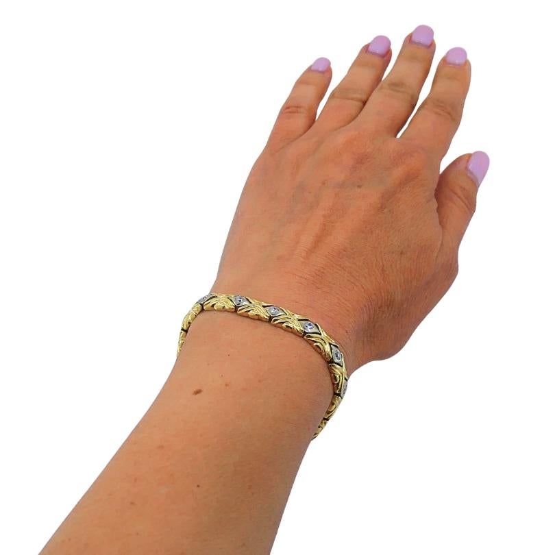 Ce bracelet bicolore en or 14 carats présente un motif alterné complexe d'or jaune chaud et d'or blanc froid, magnifiquement rehaussé de diamants ronds étincelants. Le design présente un mélange harmonieux de styles classiques et contemporains, ce