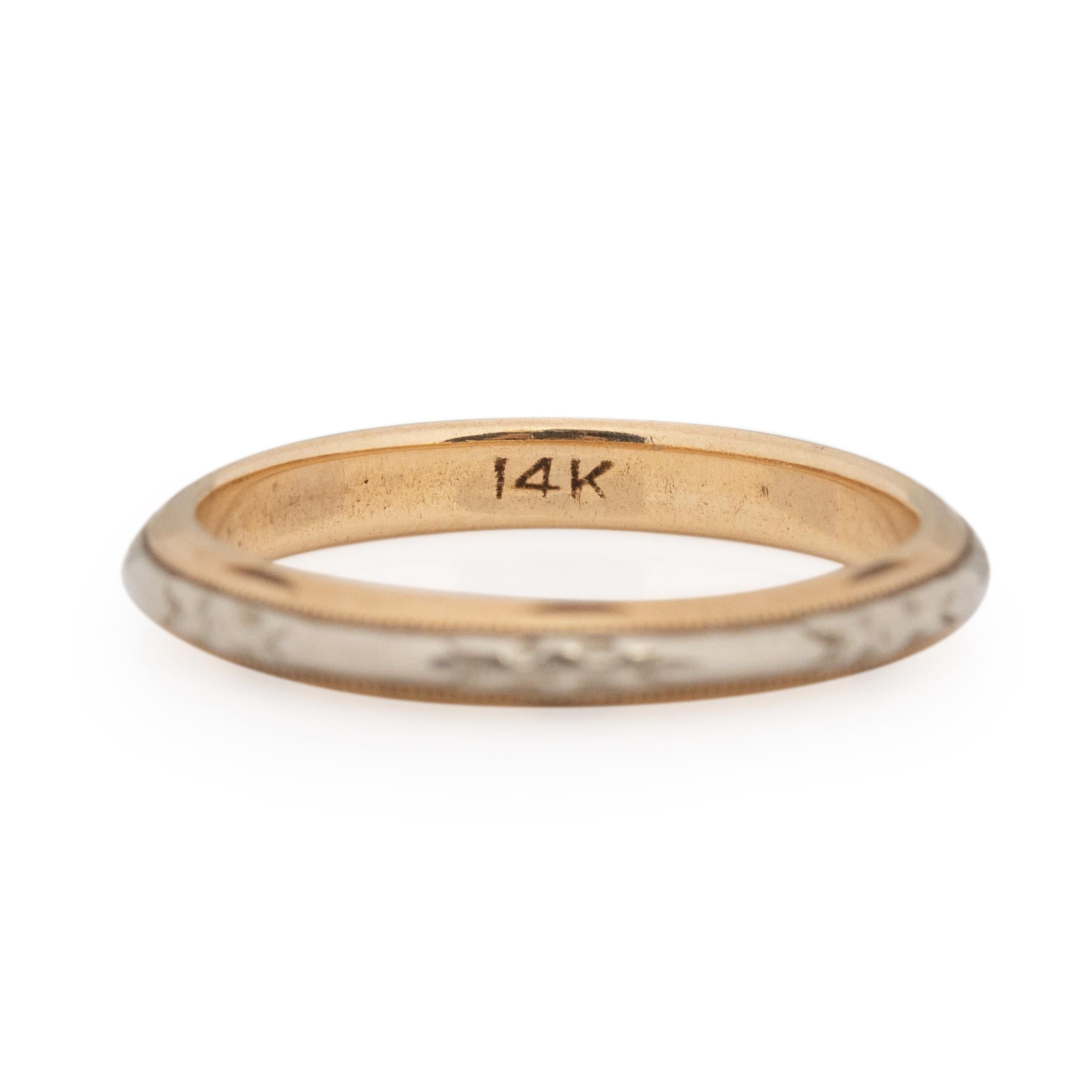 This two tone band is crafted in 14K white and yellow gold. The base of the ring is yellow gold along the center, raised in to the knife edge is a white gold strip that has an elegant embossed design. The knife edge gives this ring a thin and tall