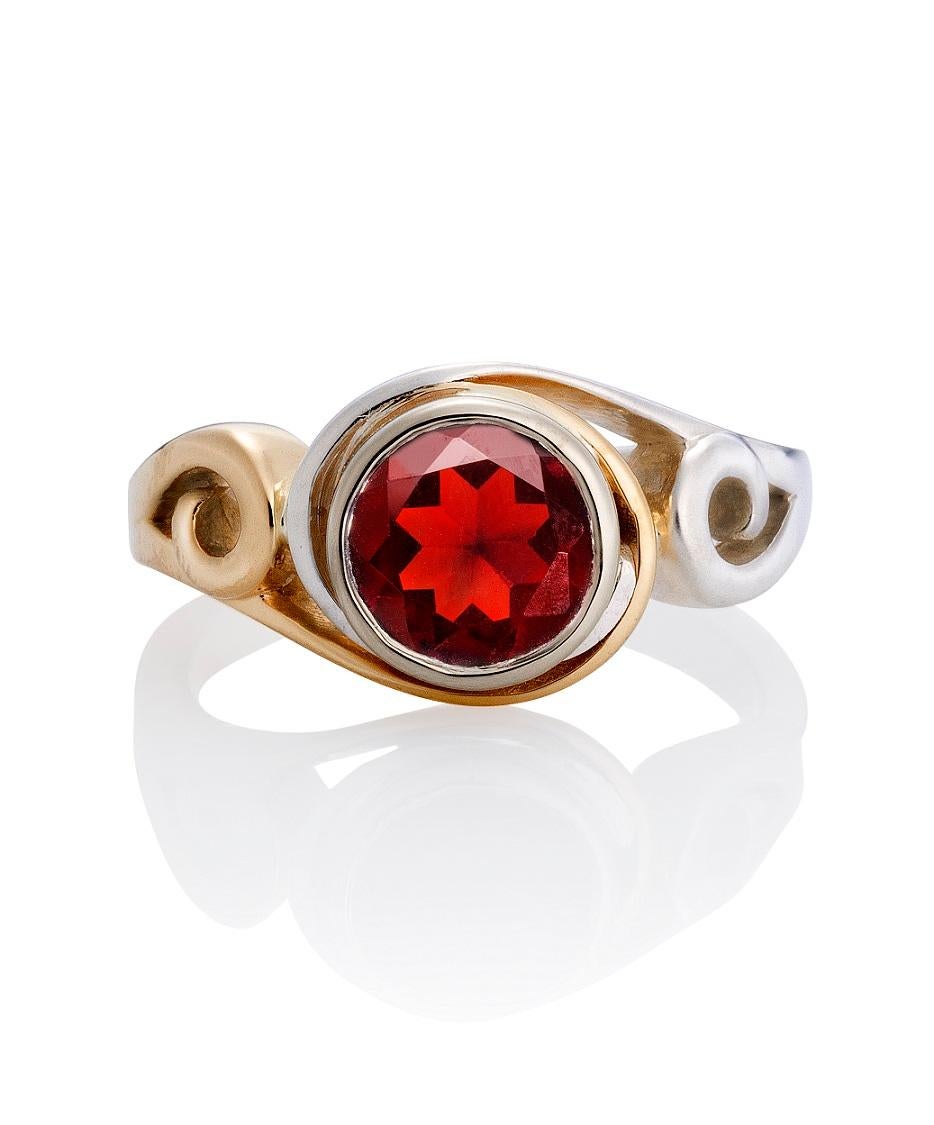 This Nebula Fashion Ring, is a two tone ring made in 14ky and platinum sterling silver. Bezel-set in the center is a beautiful, 8mm garnet. Surrounding the center stone are interlocking spirals that wrap around the garnet. The ring is finished with