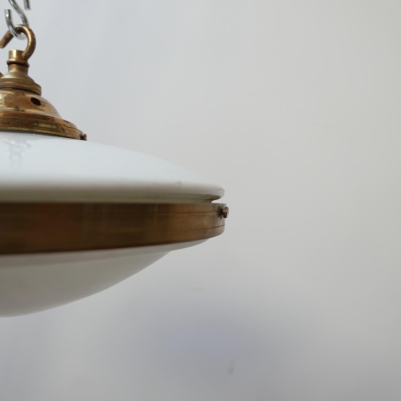 A two tone flying saucer pendant light. 

German, c1930s. 

Brass rim and gallery. 

Opaline glass top, etched glass base. 

Re-wired and PAT tested. 

Dimensions: 30 diameter x 18 height in cm. 

Delivery: POA.

