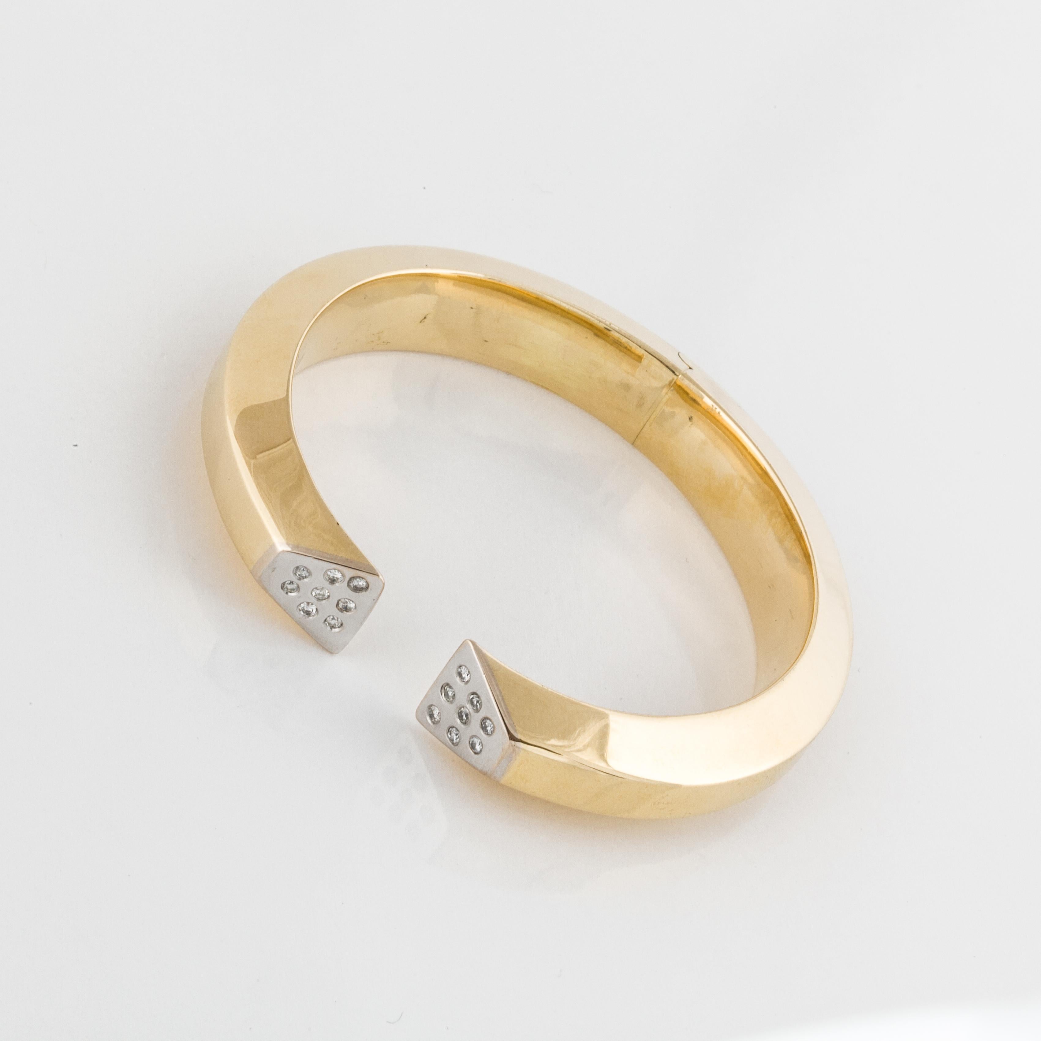 Modern hinged bracelet in 18K yellow gold with round diamonds set in 18K white gold.  There are sixteen round diamonds totaling 0.35 carats; G-H color and SI1-I1 clarity.  The top is 7/16 inches wide and the inside diameter is 2 3/16 inches.  