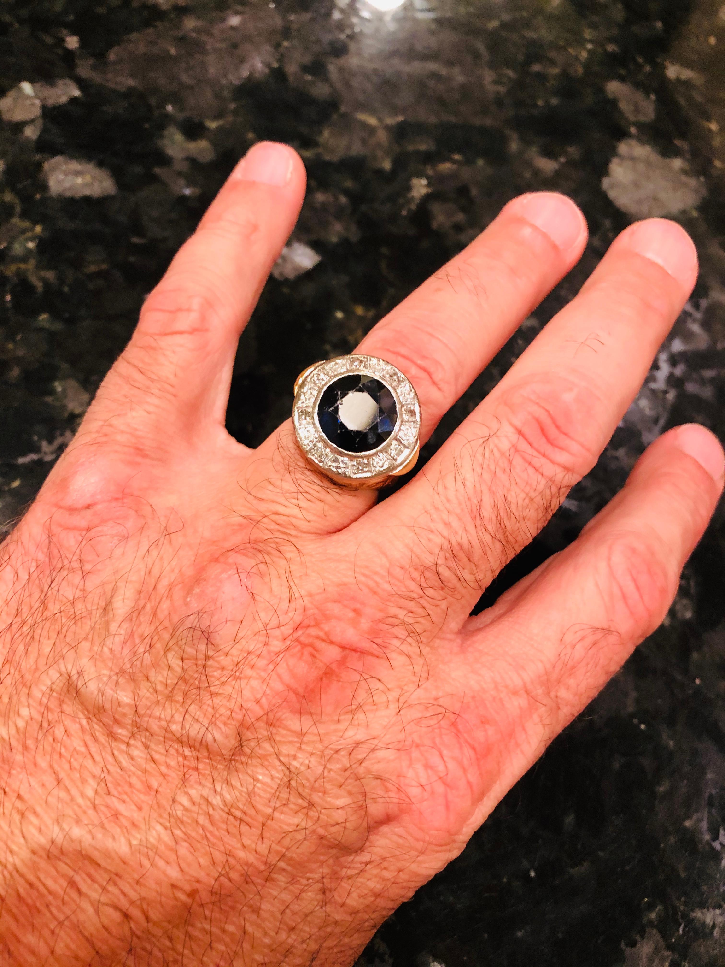 Anello in oro bicolore Diamonds Mine che circondano uno zaffiro Sedici diamanti taglio miniera che circondano una pietra nera, probabilmente uno zaffiro. Il tutto ha un peso totale di 19,5 grammi ed è una misura 8,25. La faccia dell'anello misura