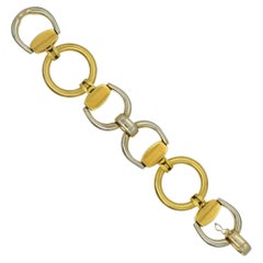 Pulsera de eslabones tipo estribo en oro bicolor.