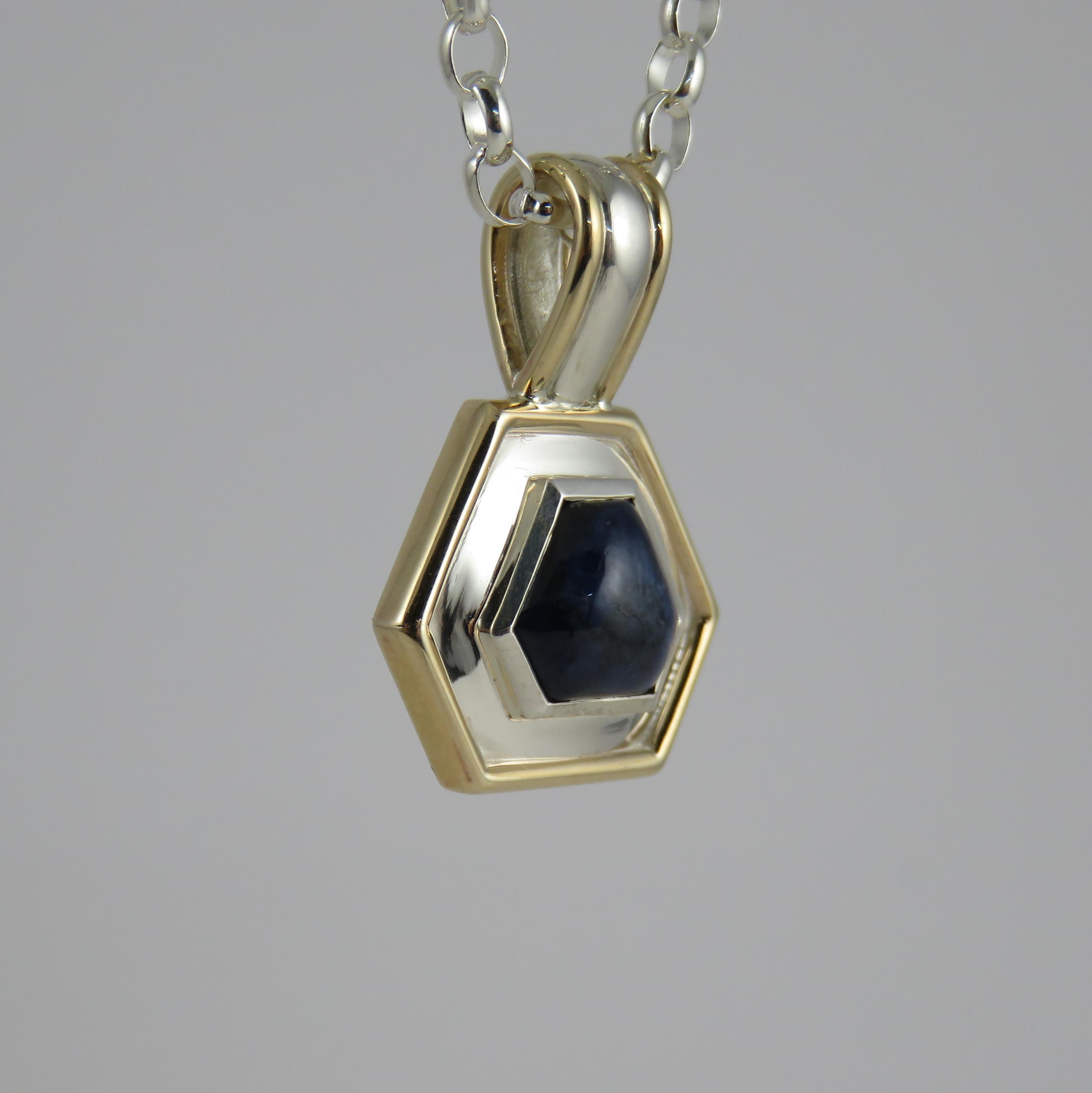Small but perfectly formed, this beautiful and unique piece of jewelry combines sterling silver and 9k yellow gold, along with a blue cabochon sapphire, creates an interesting contrast. The use of two-tone metals adds visual interest and depth to