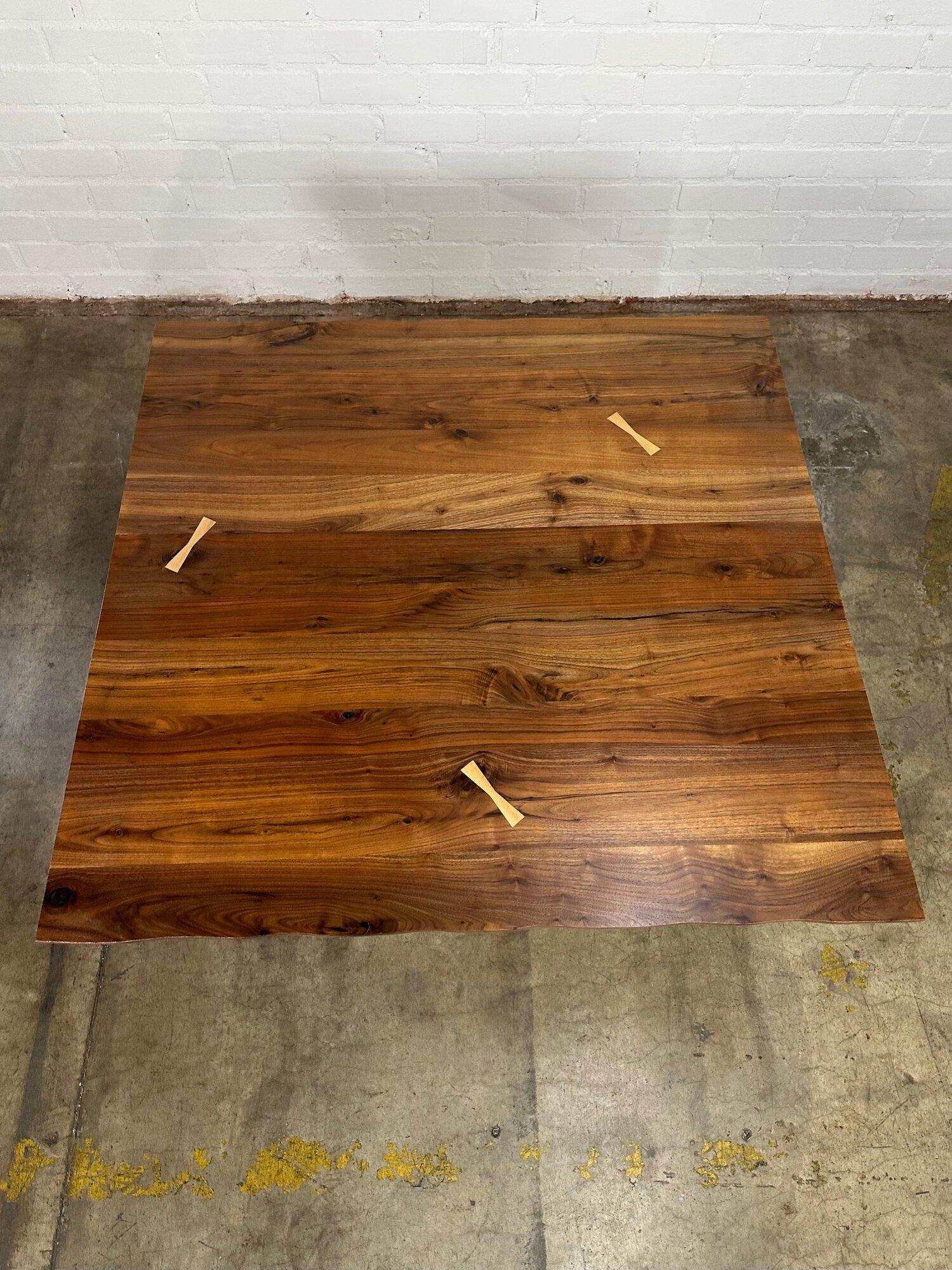 Measures: W48 D47.5 H30 KC28.5

Reimagined walnut slab compact dining table. Surface was salvaged, refinished and inlay was added to help structural integrity of surface. New squiggle legs were handcrafted and assembled in house. Item shows in