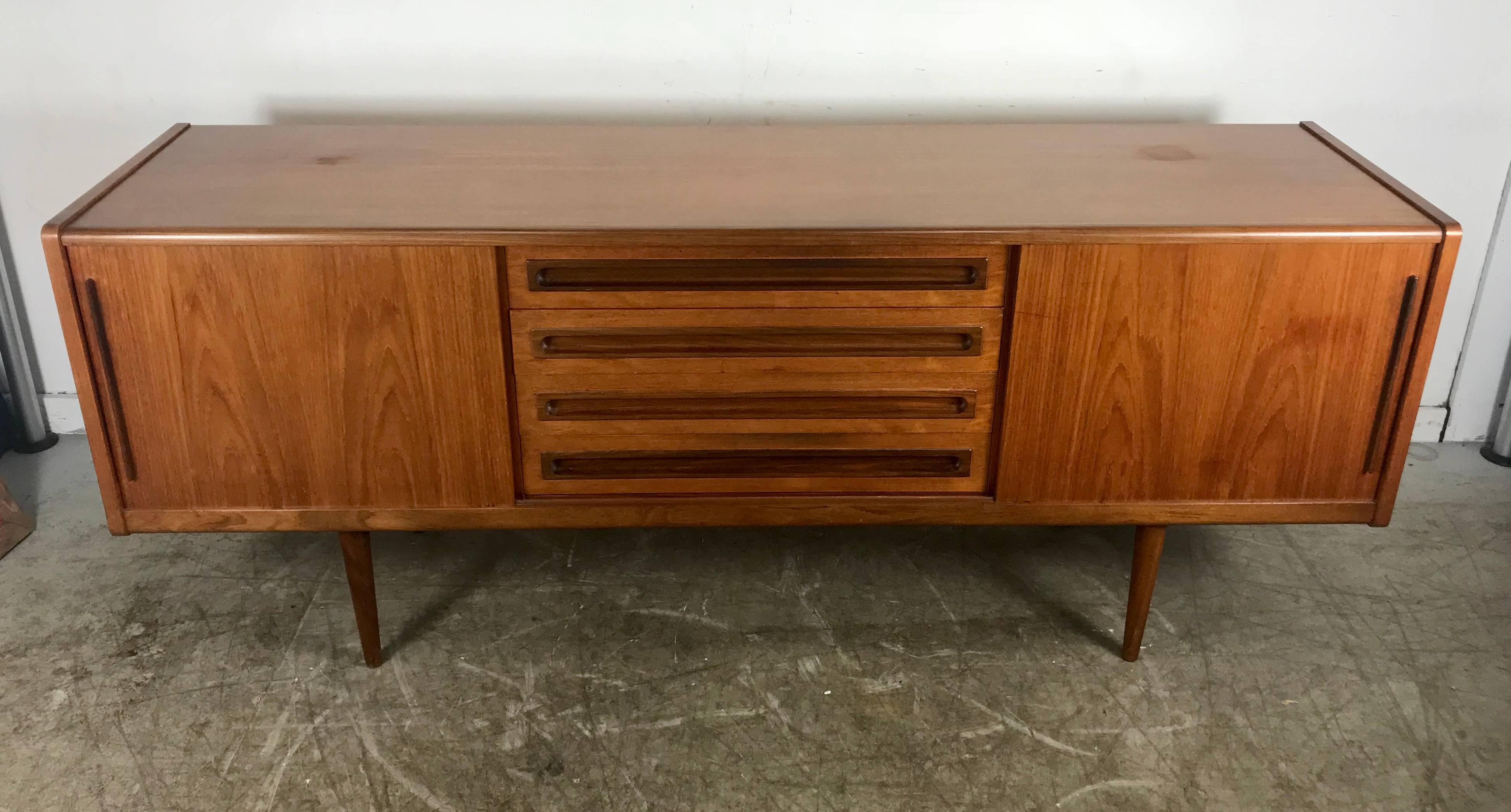 Quality Danish modern / Scandinavian teak credenza or buffet has a gorgeous patina and graining, as well as a beautifully finished back. The centre four drawers are solid teak drawer fronts dovetailed with wood frame drawer construction. Note the