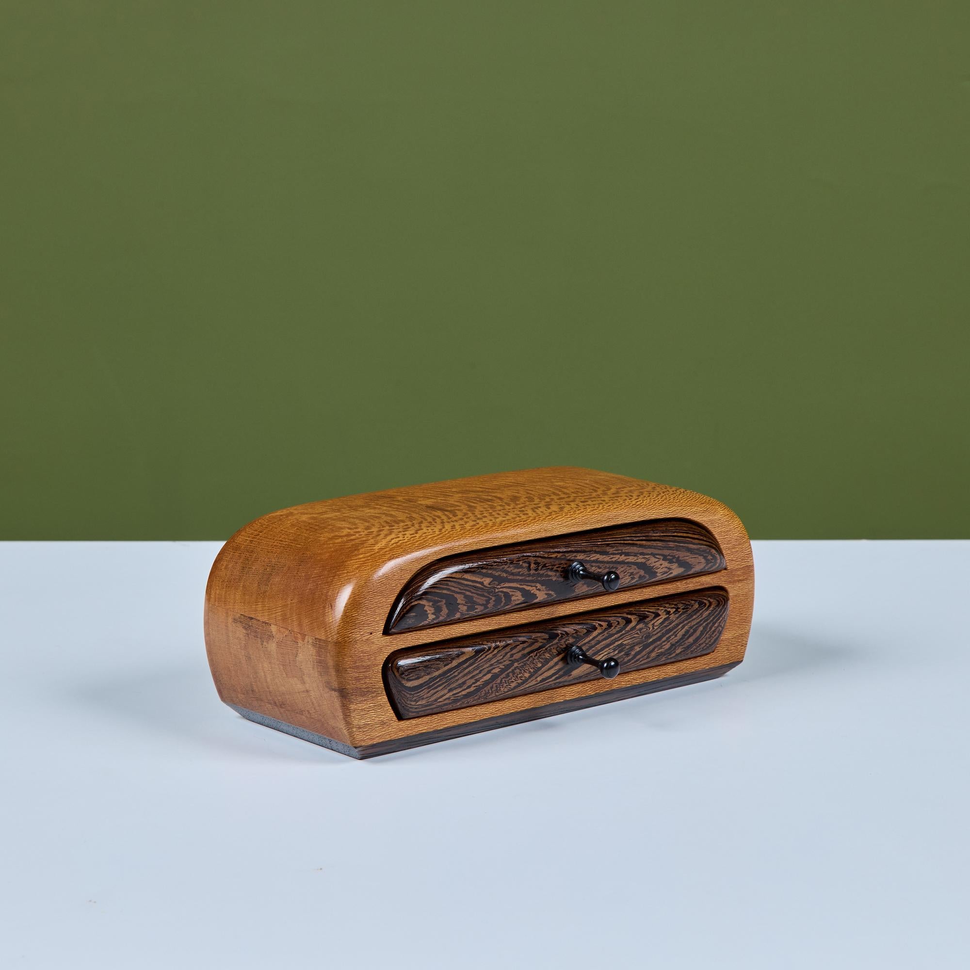 Boîte à bijoux Studio craft en palissandre et acajou, c.C. 1987, avec un boîtier en acajou et une base et des tiroirs en palissandre contrastés. Chaque tiroir est doté d'une tirette allongée et est doublé d'un daim vert.  Signé Jayo '87.

Avis de