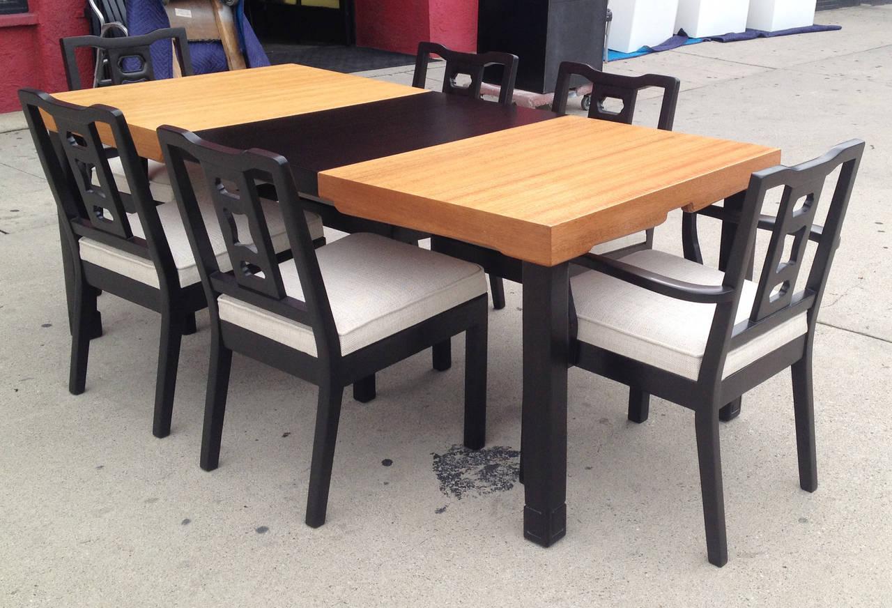 This beautiful Asian influence dining set features an extendable table and six chairs. The wood table features a blond natural mahogany surface and four black stained legs that end in a stylized scroll. The removable black extension adds an element