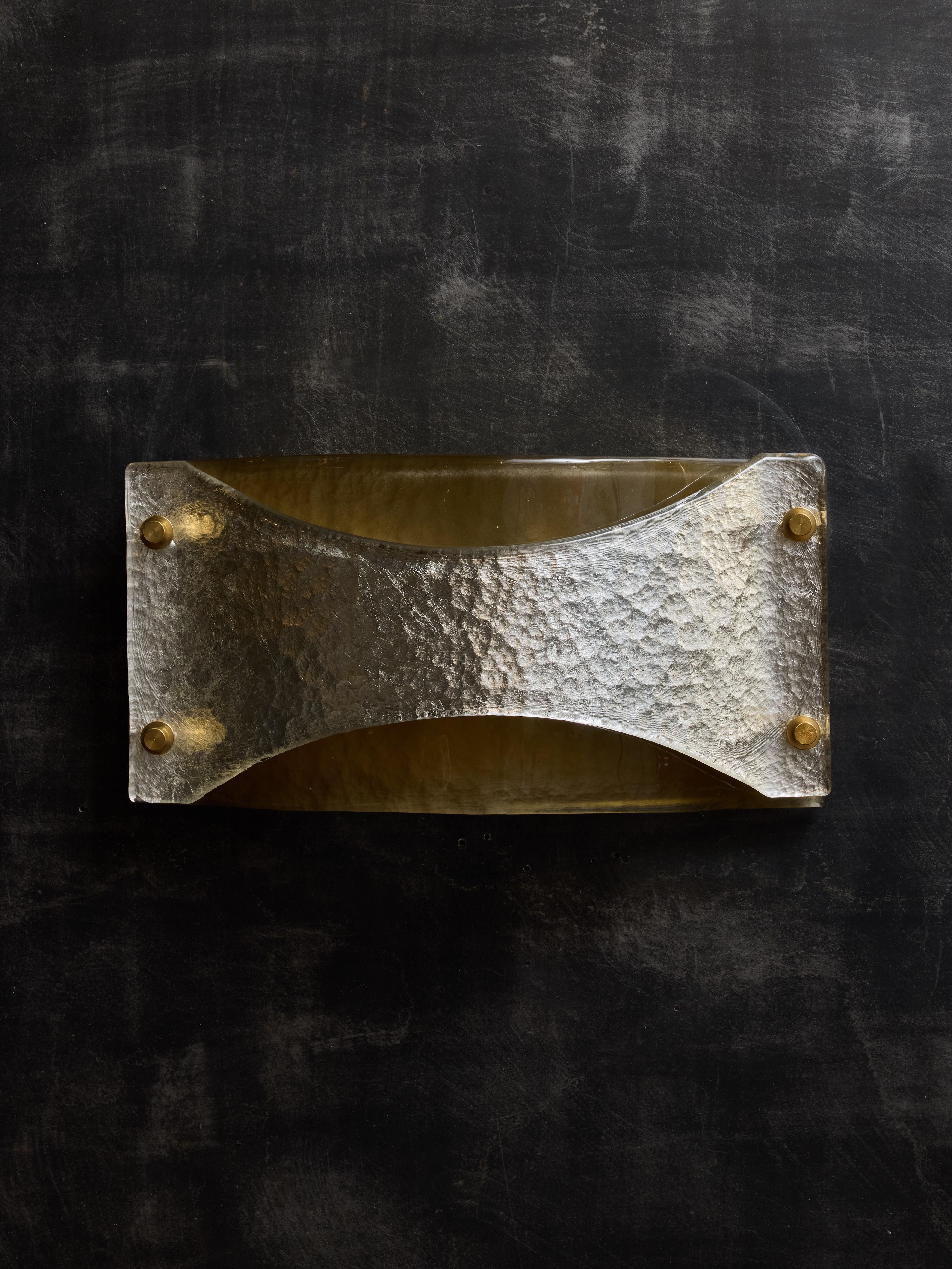 Appliques murales composées d'une plaque arrière en laiton, recouverte de deux panneaux en verre de Murano, l'un teinté en ambre fumé et l'autre en couleur argent, maintenus en place par des vis décoratives en laiton.

Elles peuvent être placées