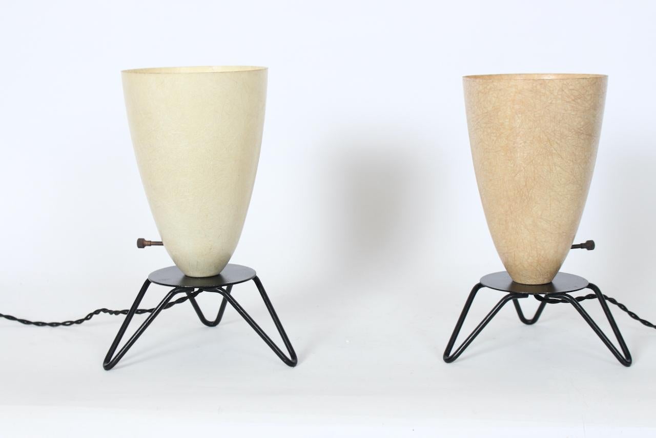 Two 1950's Coffee & Cream Shade, Black Wire Tripod Base, Uplights, Shelf Lights, Accent Lights. In the manner of Tony Paul. Featuring slight varied height Fiberglass bullet cone Shades, atop round Black enameled metal discs and tripod Hairpin legs.