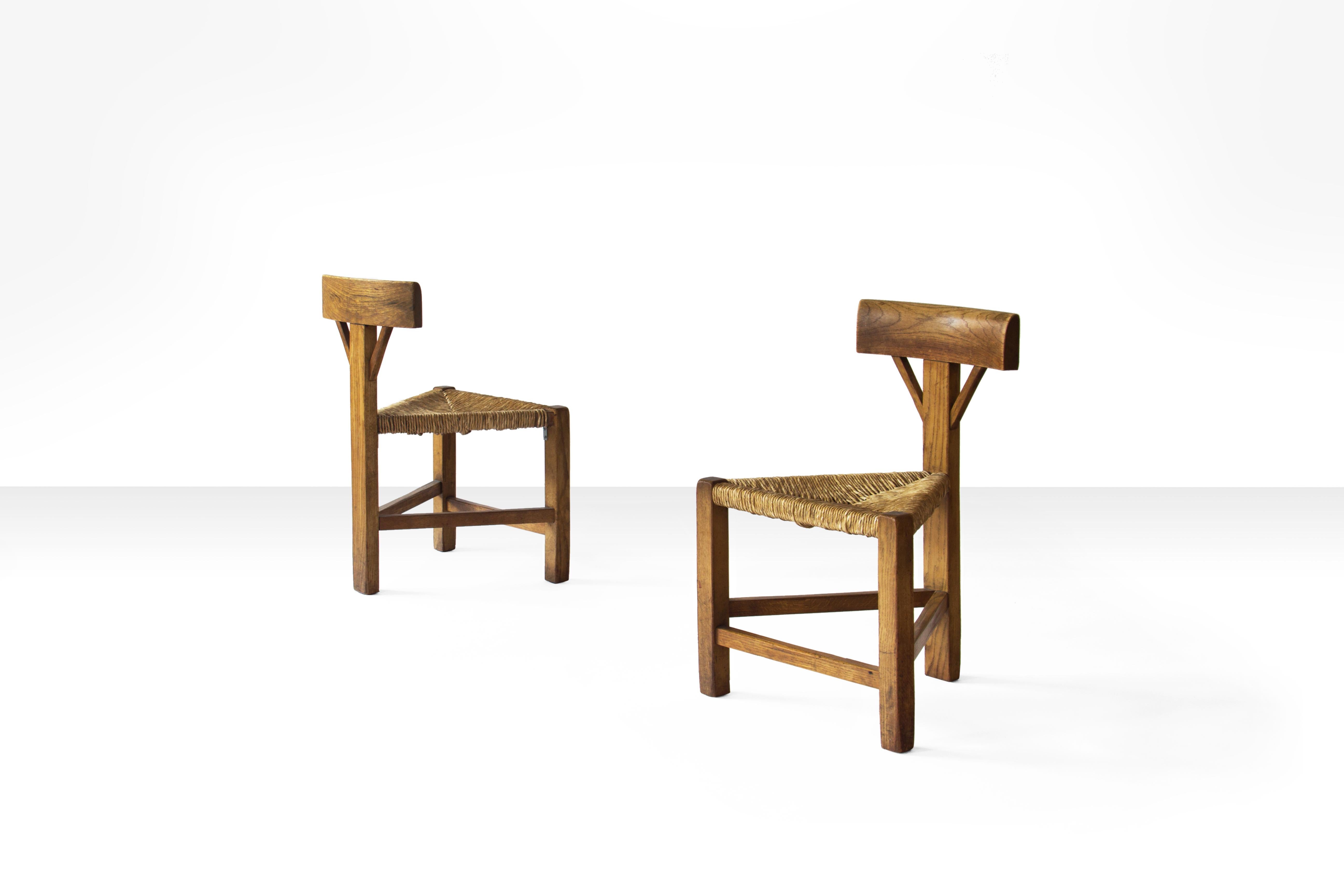 Pair of triangular midcentury chairs in oak and cane in the manner of Charlotte Perriand. Most likely they originate from The Netherlands ca 1960s-1970s. It's also possible that they are from France. The chairs are in beautiful vintage condition and