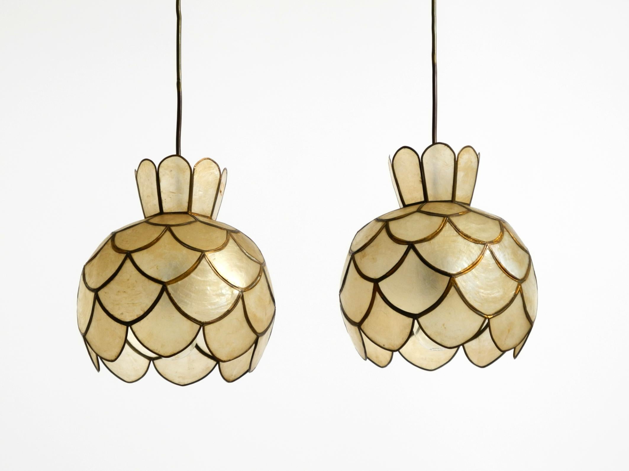 Une paire de lampes suspendues florales très élégantes et d'une beauté époustouflante, faites de coquillages capiz.
Les abat-jour sont fabriqués à la main aux Philippines dans les années 1960 à partir de laiton et de coquillages capiz. Chaque teinte
