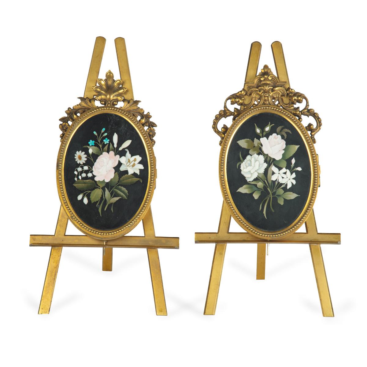 Two very similar pietra dura and ormolu photograph frames on easels,  each of oval form with a pietra dura panel inlaid with a posy of roses, stephanotis and forget-me-not on a black ground, opening to reveal two photograph frames and set in