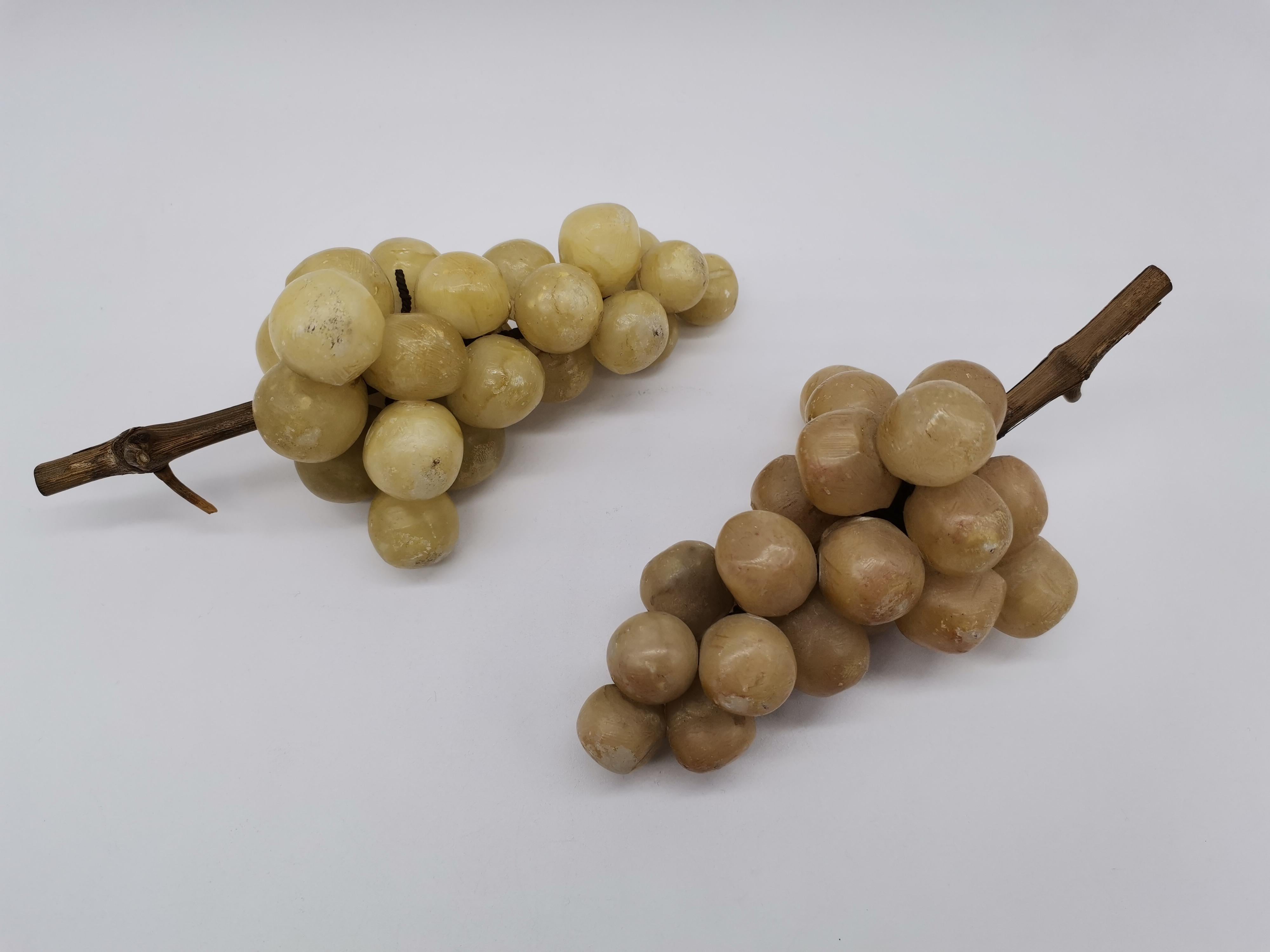 Two vines of grapes. One is a little brighter than the other. Made of alabaster and wood.