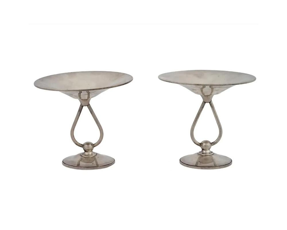 A pair of two vintage Art Deco sterling silver tazzas, each featuring a bowl mounted to a round base with two curved feet. Marked underneath. Circa the early or mid 20th century. Total weight for pair: 542 g. Vintage Tazzas And Silverware