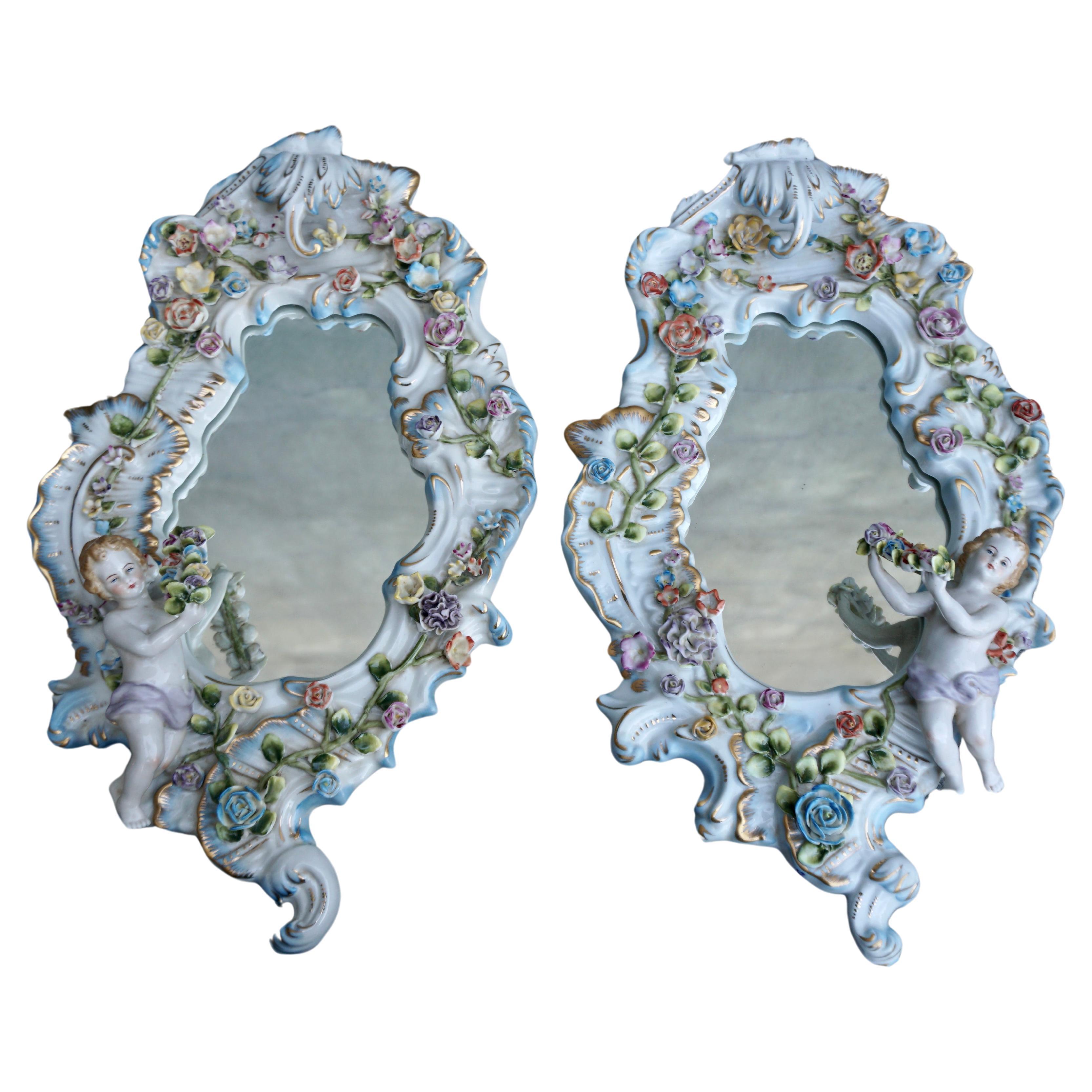 Vintage Capodimonte porcelain framed wall mirror; with gilded accents,and elaborately decorated with a variety of delicately crafted flowers and cherub perched on the corners.

There can be some small leaves missing given the period of dating and