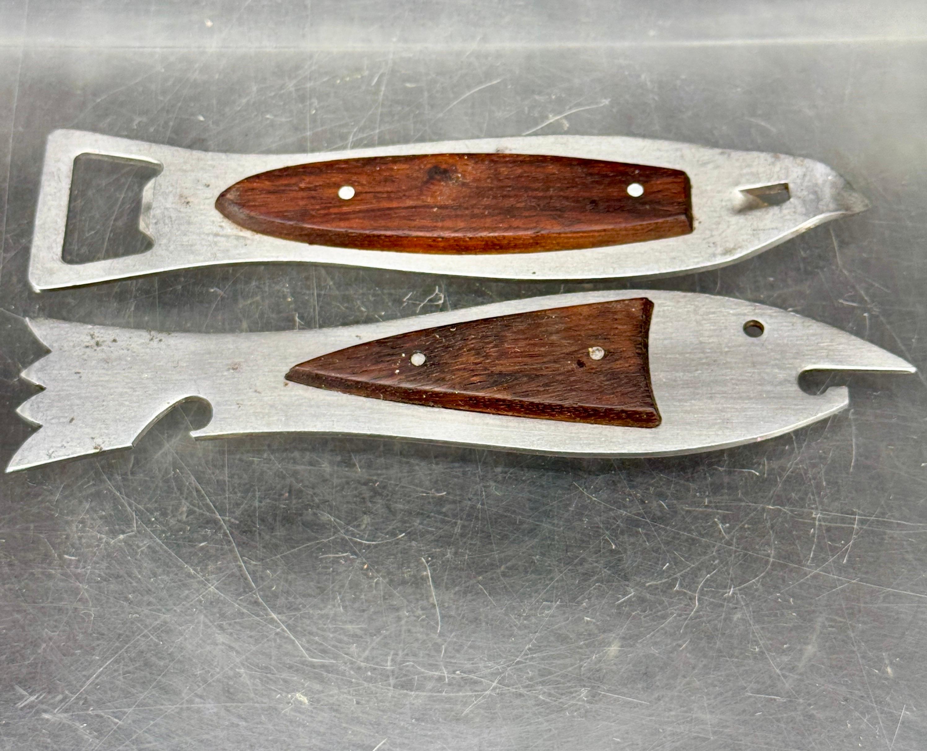 Pair of Mid-Century Modern stainless steel and teak wood openers. There is a a shark and a fish in this set. One is a bottle, other can opener. These vintage barware pieces are made in Denmark and the steel is marked Japan. 