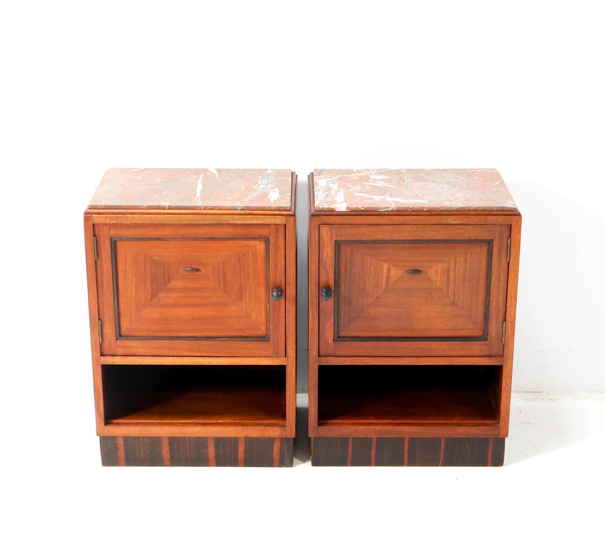 Stunning and rare pair of Art Deco Amsterdamse School nightstands or bedside tables.
Striking Dutch design from the 1920s.
Solid walnut and original walnut veneer base with solid macassar ebony knobs and decorative lining.
Original multi-colored