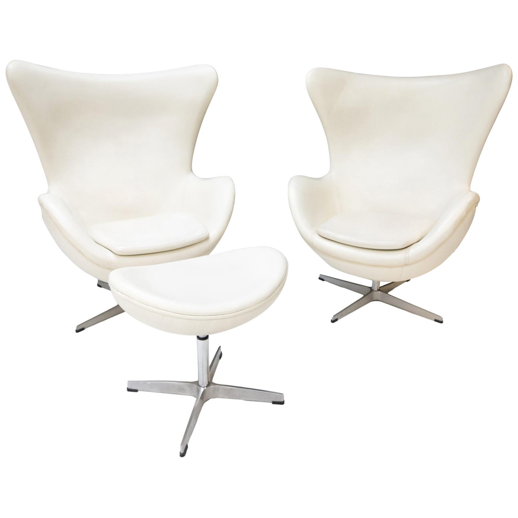 Two White Leather Egg Chairs and Footstool